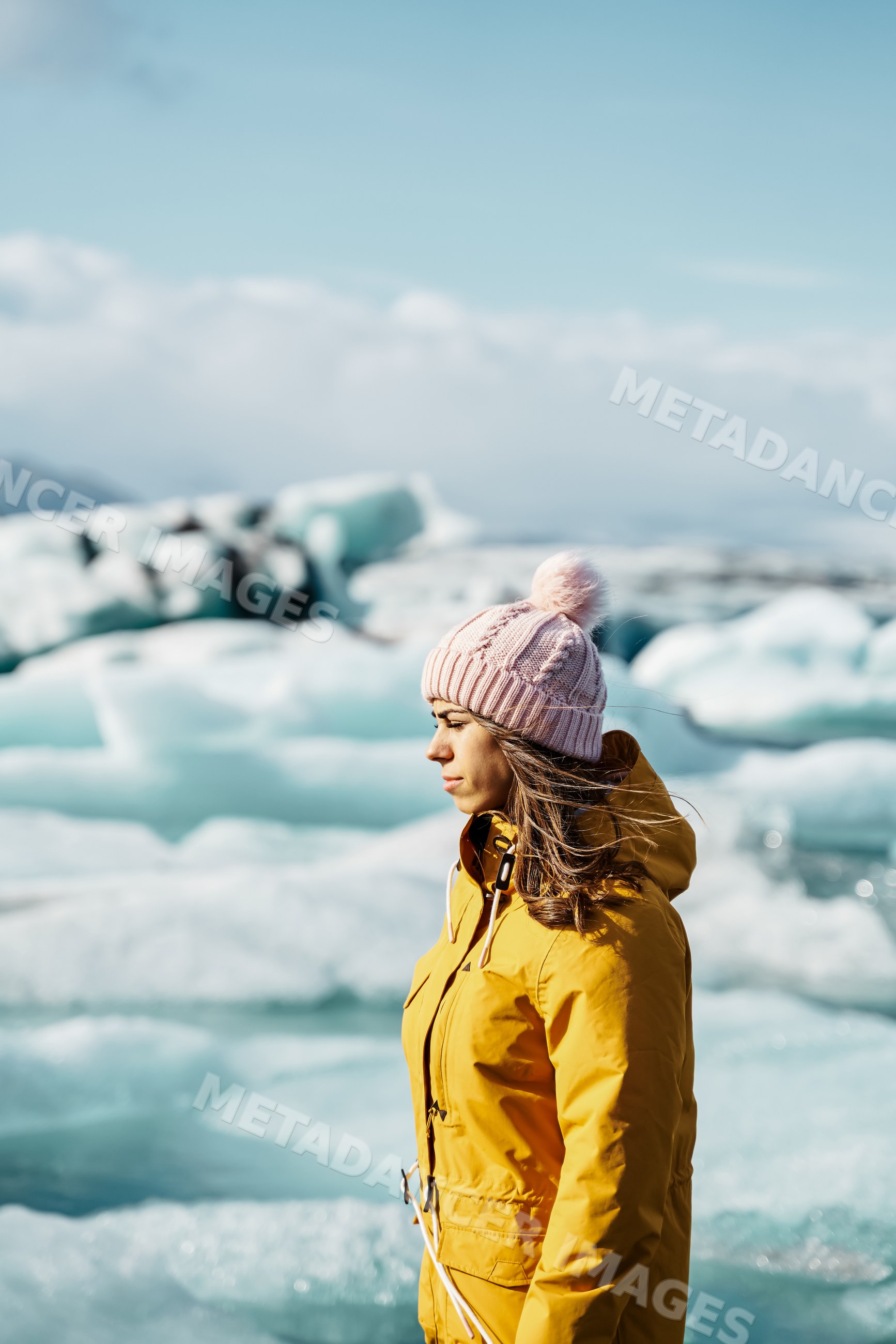 A white woman in yellow jacket standing by icebergs
