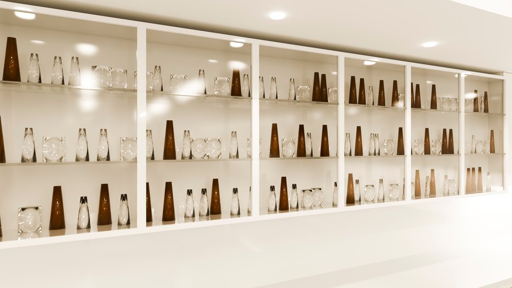 Glass and brown decorative vases arranged on white display shelf
