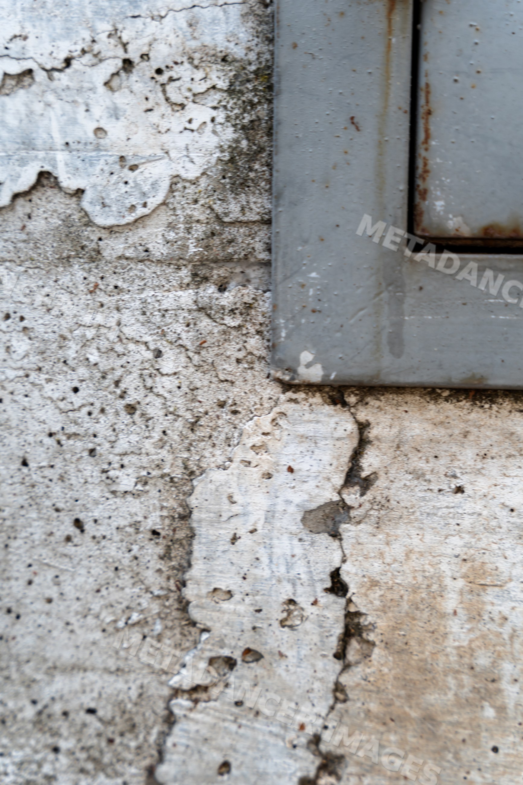 Weathered wall with peeling paint and gray metal frame corner