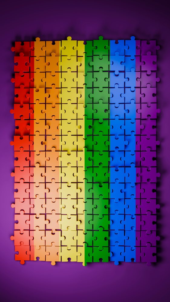 Rainbow colored jigsaw puzzle pieces assembled on purple background