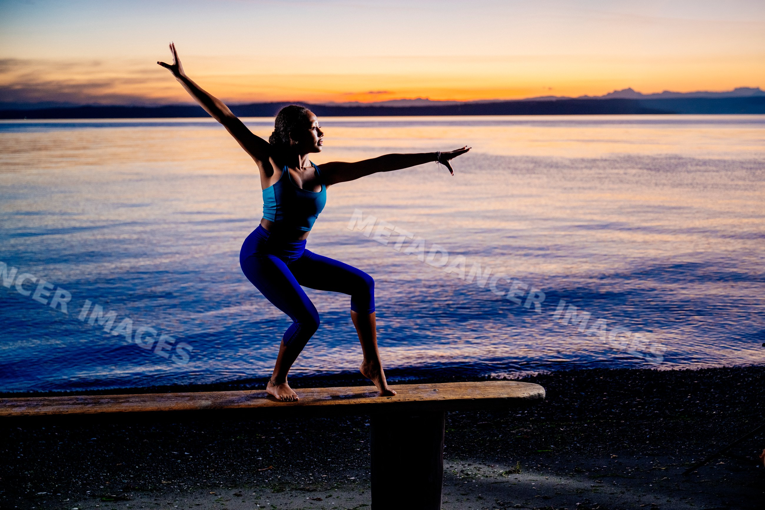 Hispanic woman balancing in yoga pose at beach sunset in a beach