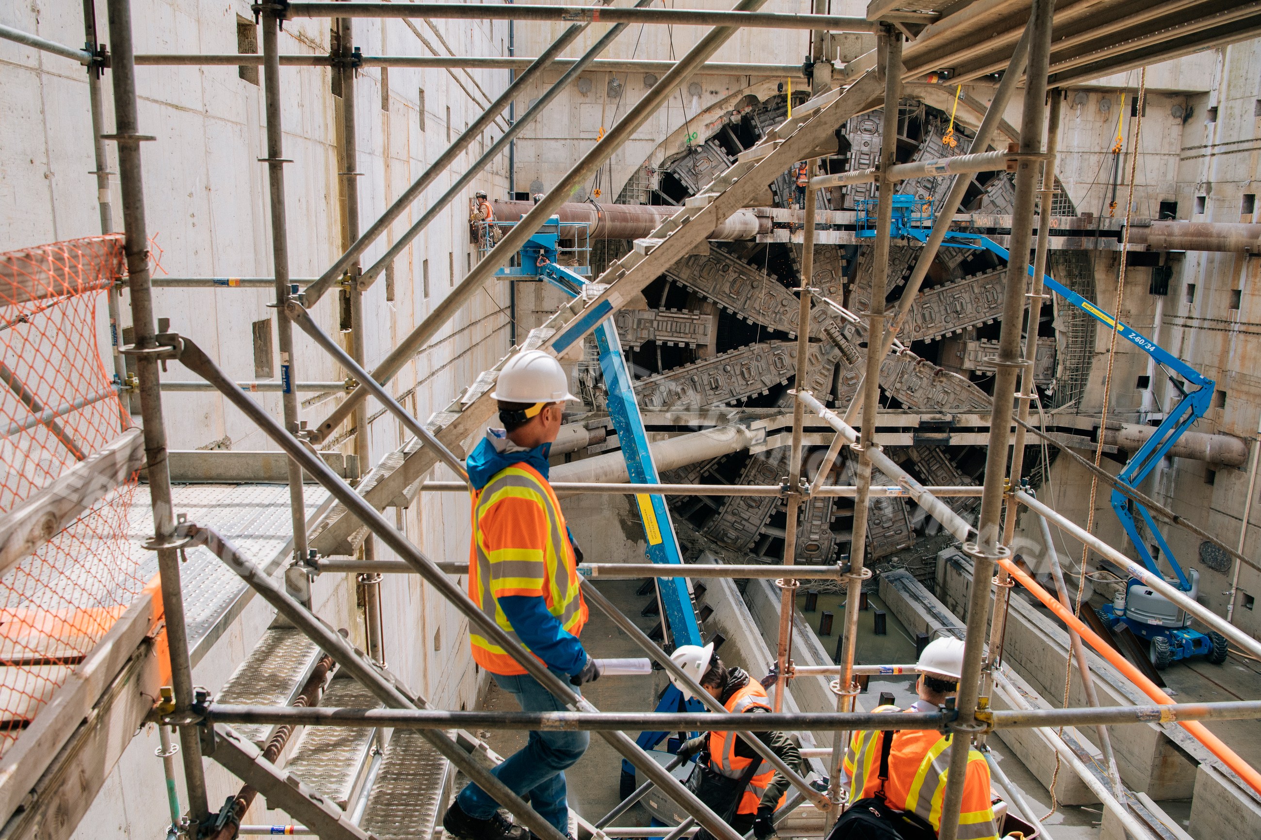Construction white workers inspect a large tunnel boring machine