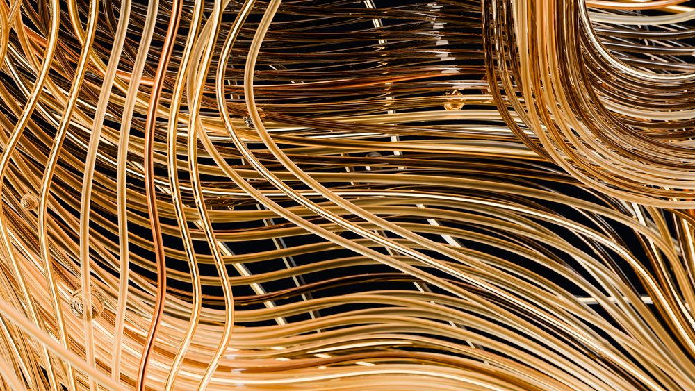 Curved golden metallic wire sculpture with intricate abstract design