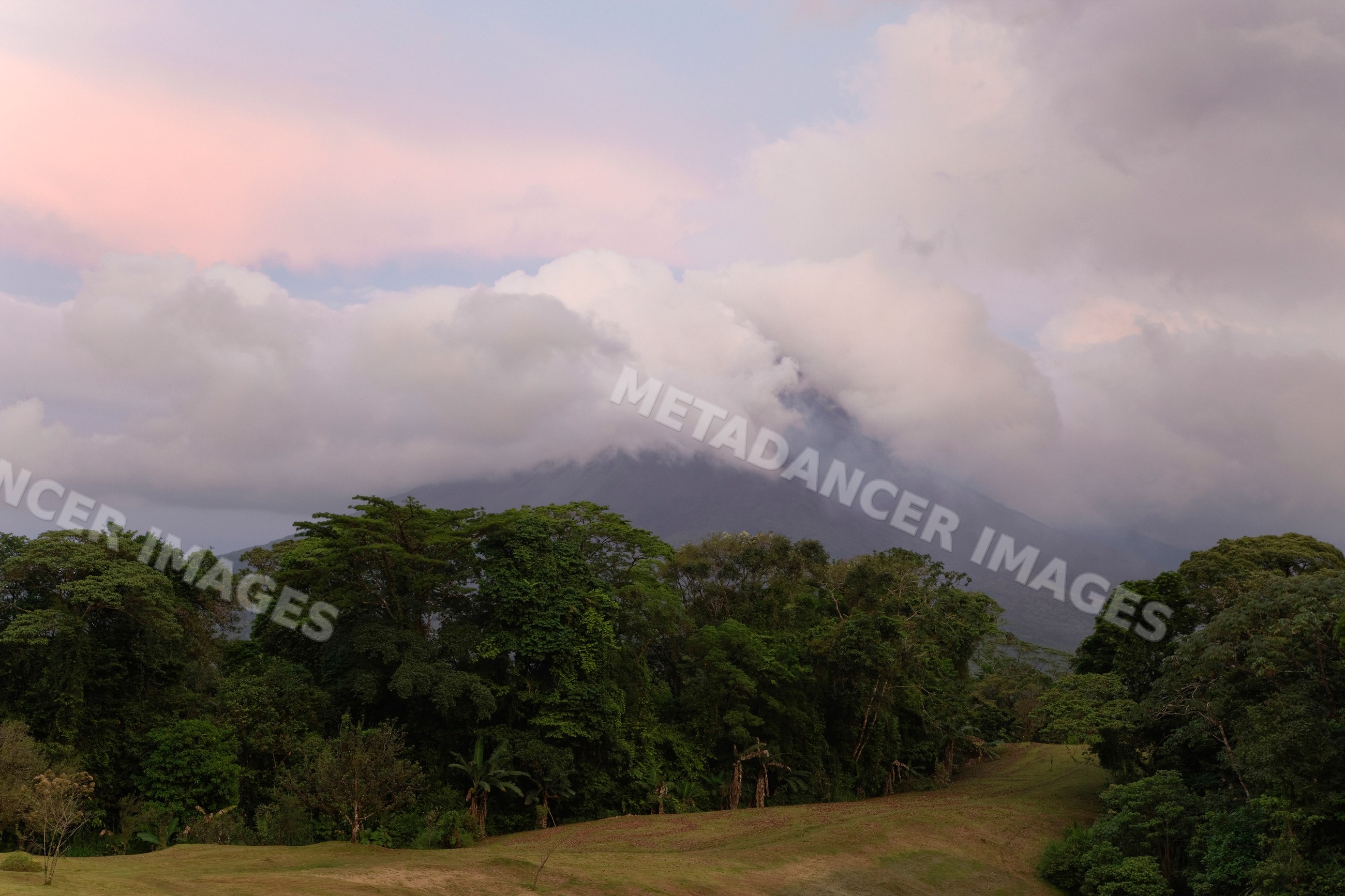 Volcano arenal with smoke and clouds over tropical forest