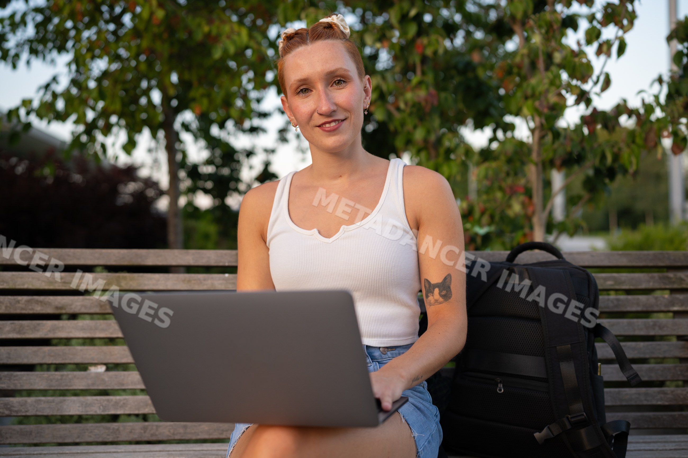 White Woman working on laptop outdoors on a bench