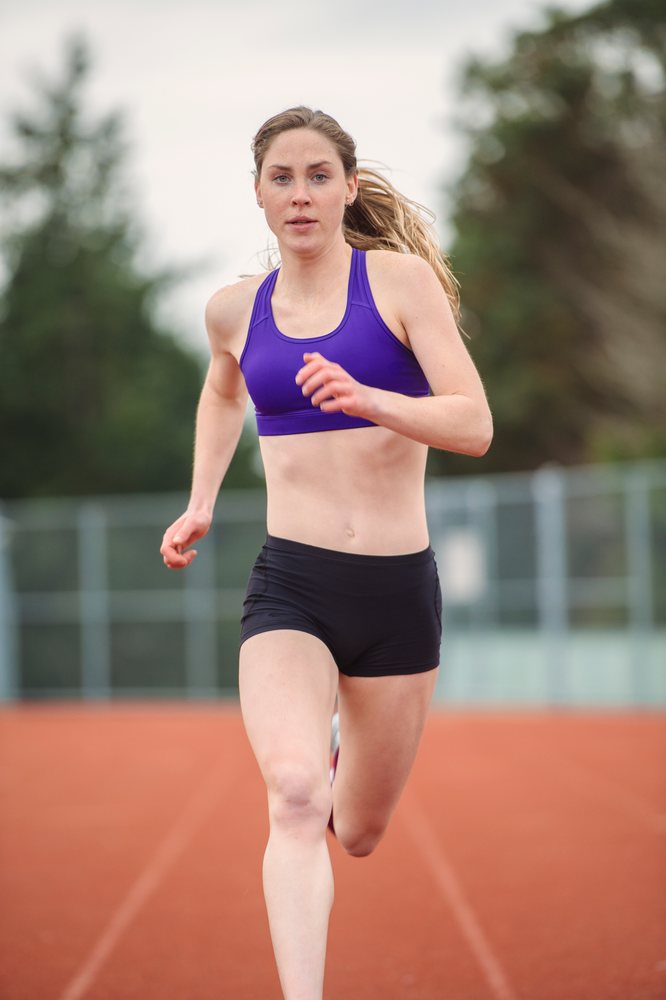 White woman sprinting on outdoor track in athletic training