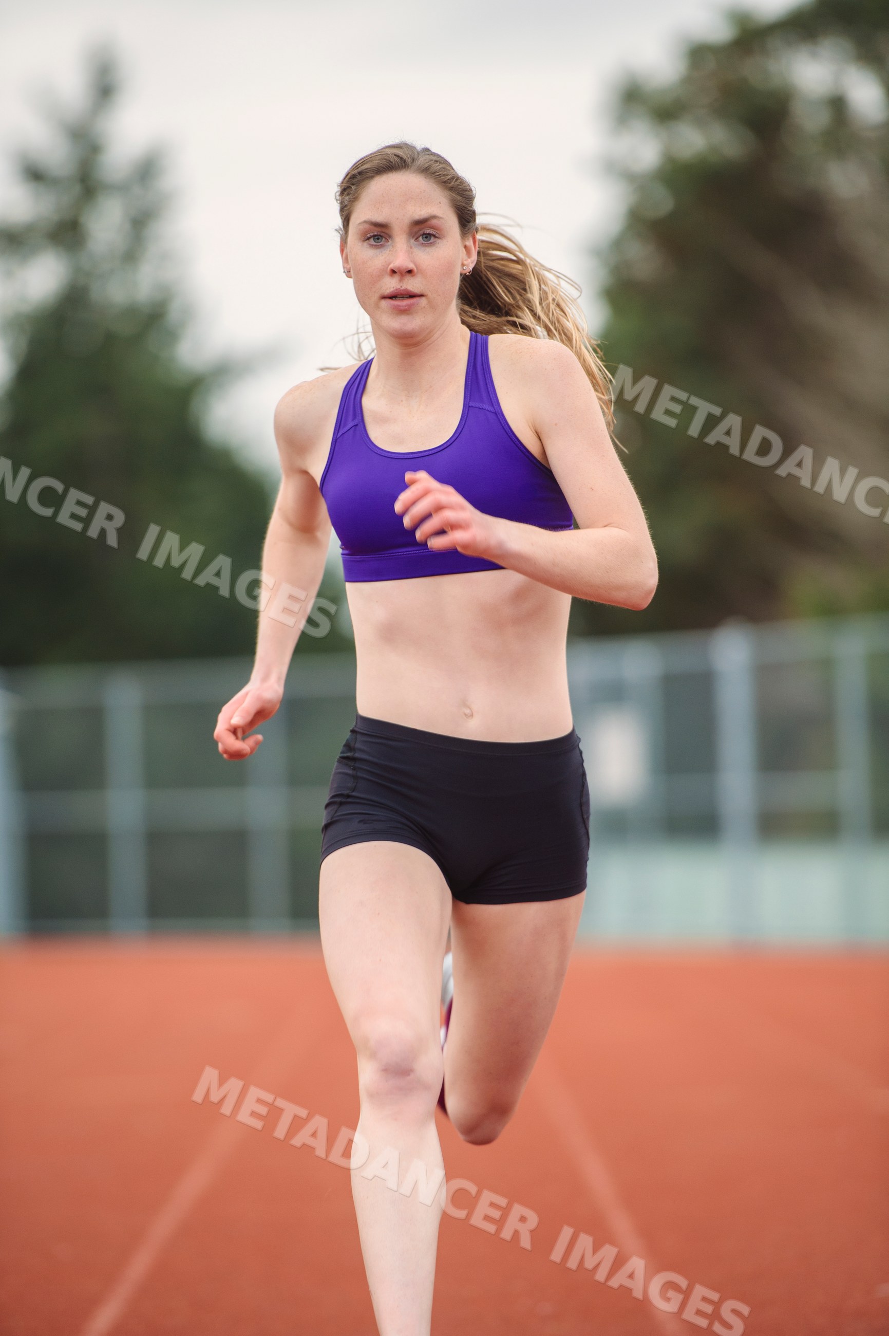White woman sprinting on outdoor track in athletic training