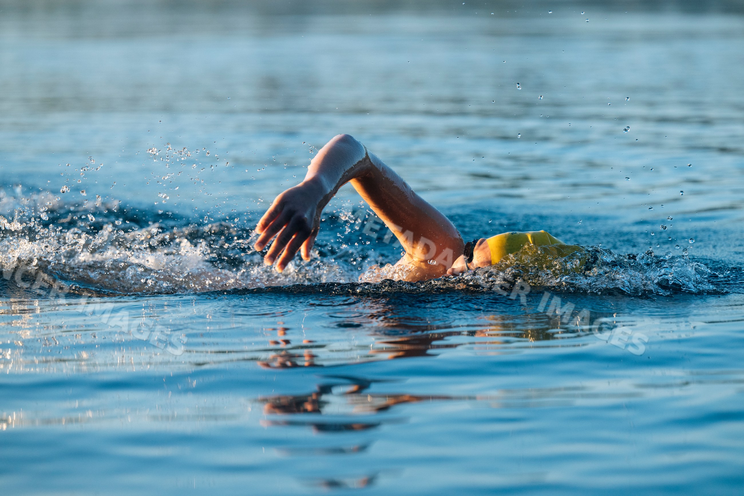 White swimmer wearing yellow cap swimming freestyle