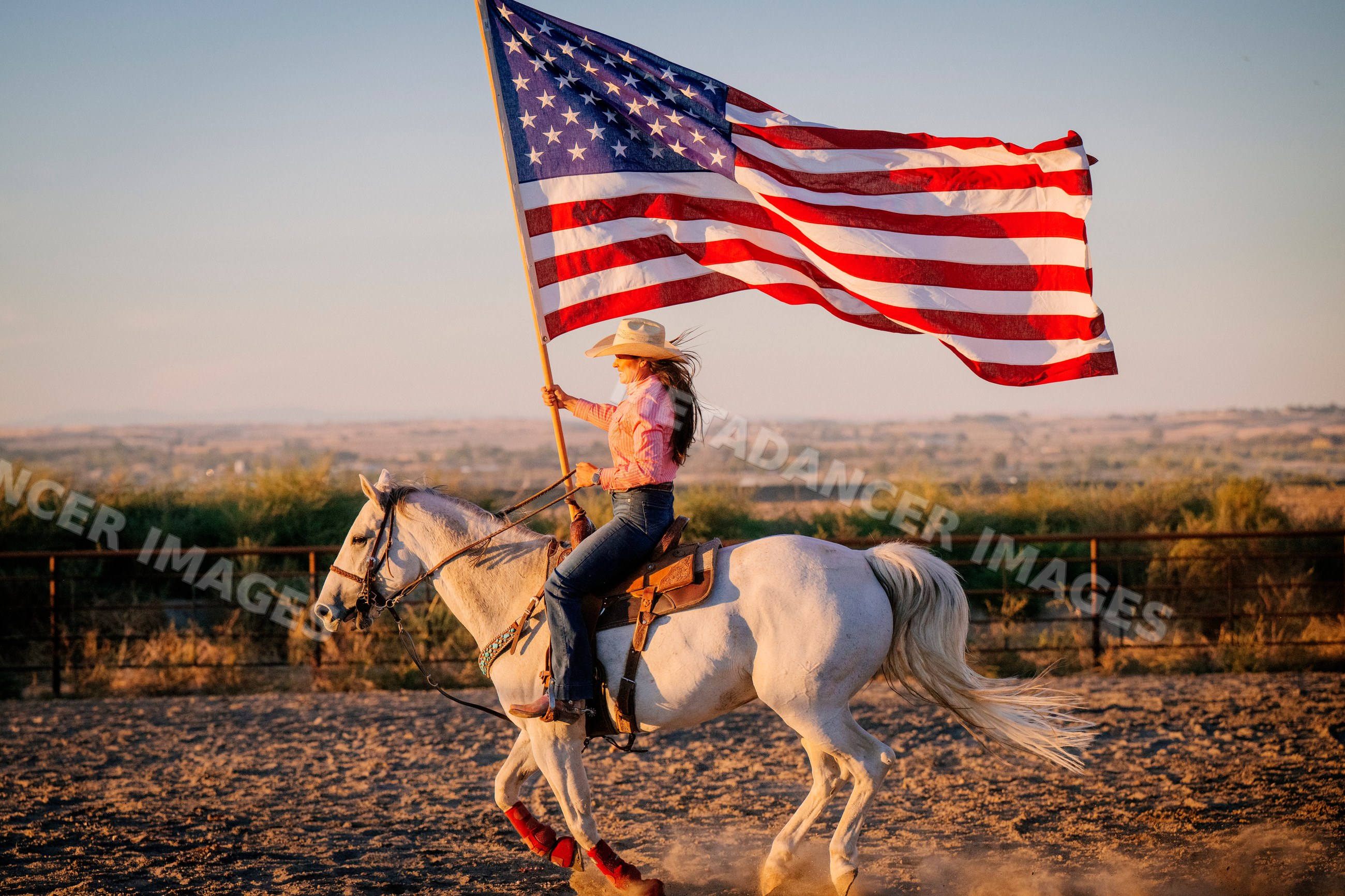 Woman riding white horse holding american flag