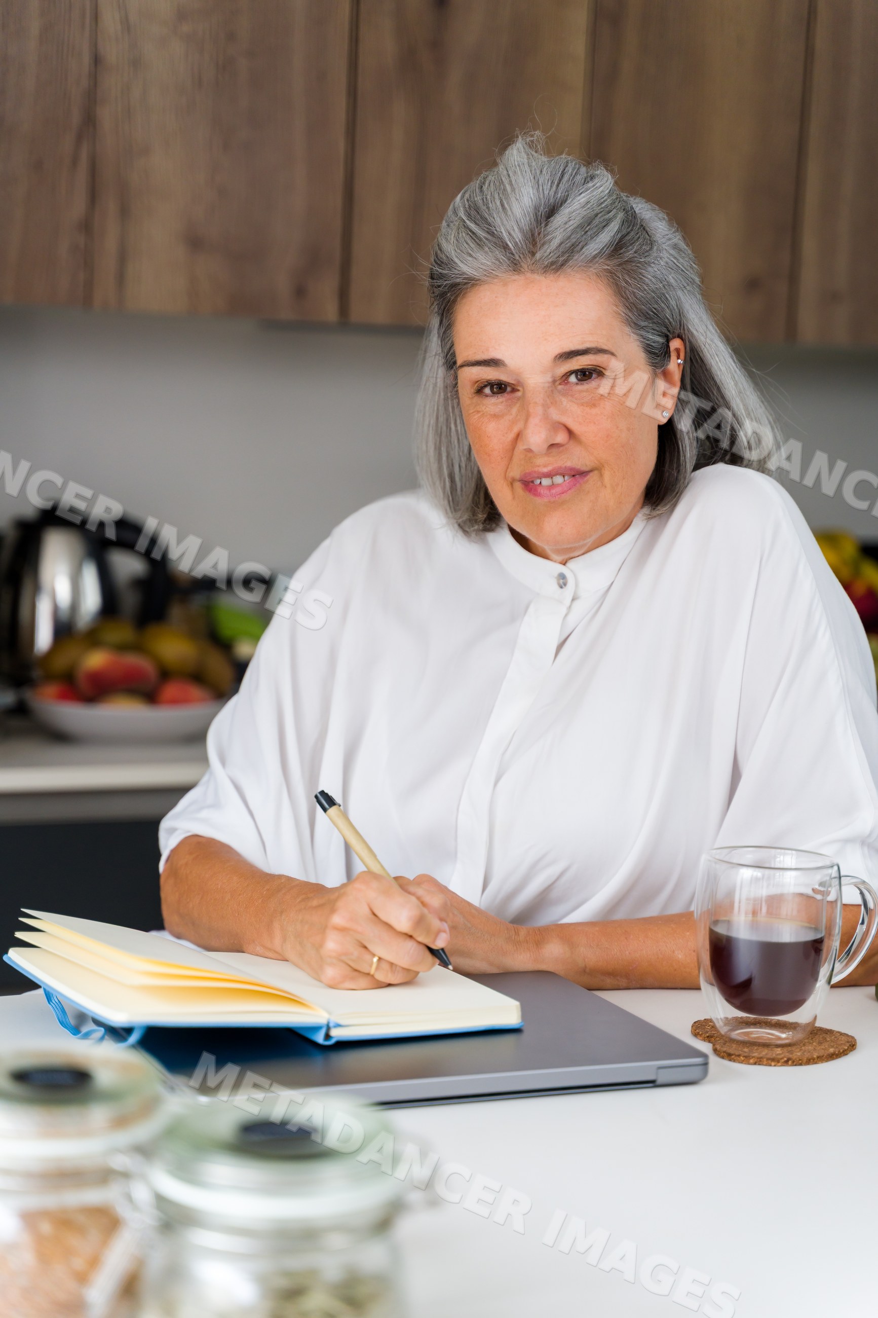 Middle-aged white woman writing in notebook at kitchen table in Spain