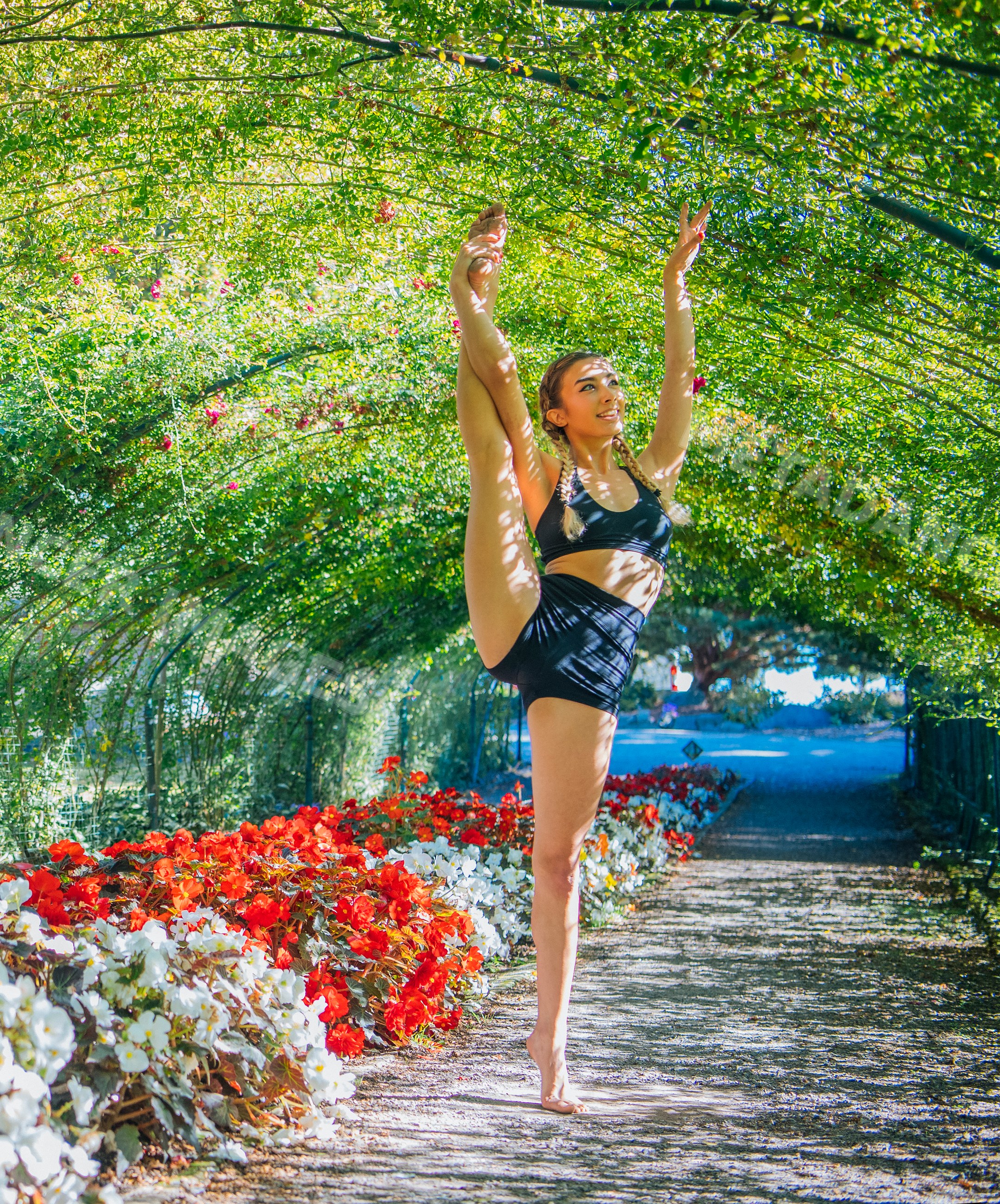 White woman contortionist stretching in a flower tunnel garden