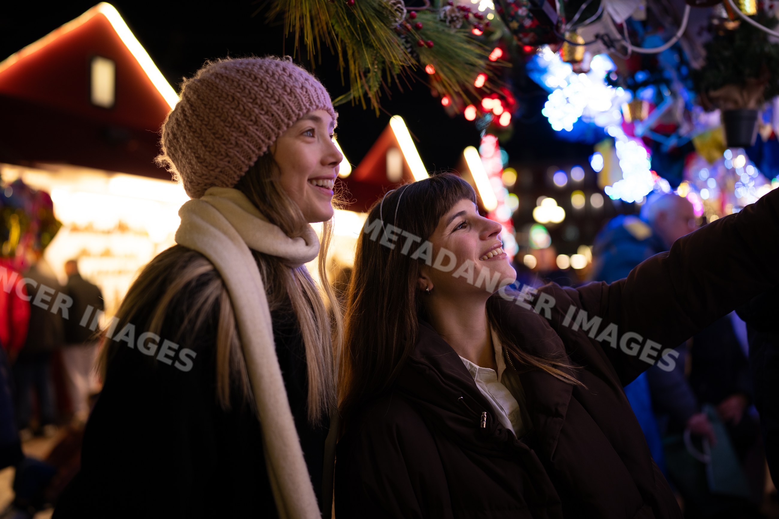 Two white women enjoying a festive holiday market night in Madrid