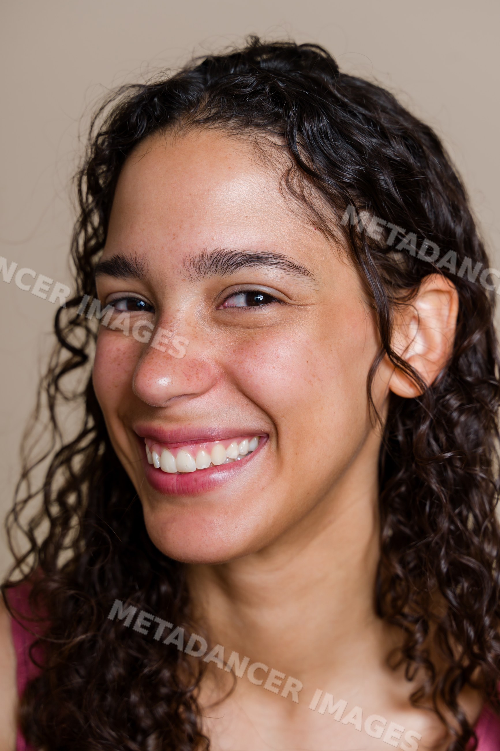 Hispanic woman smiling in close-up portrait with curly hair