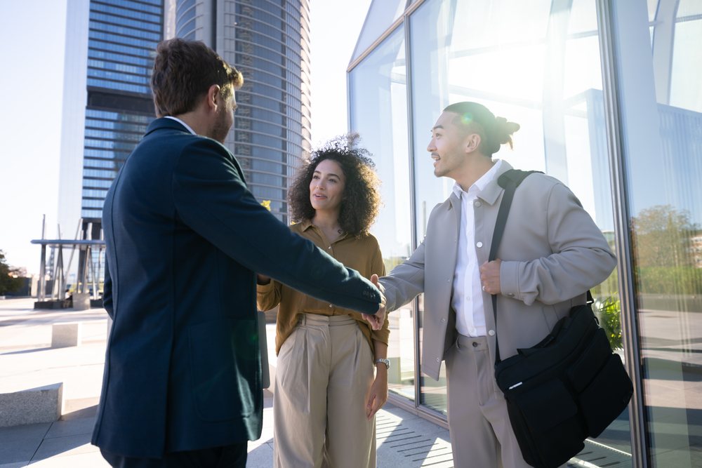 Business white professionals shaking hands outside modern building