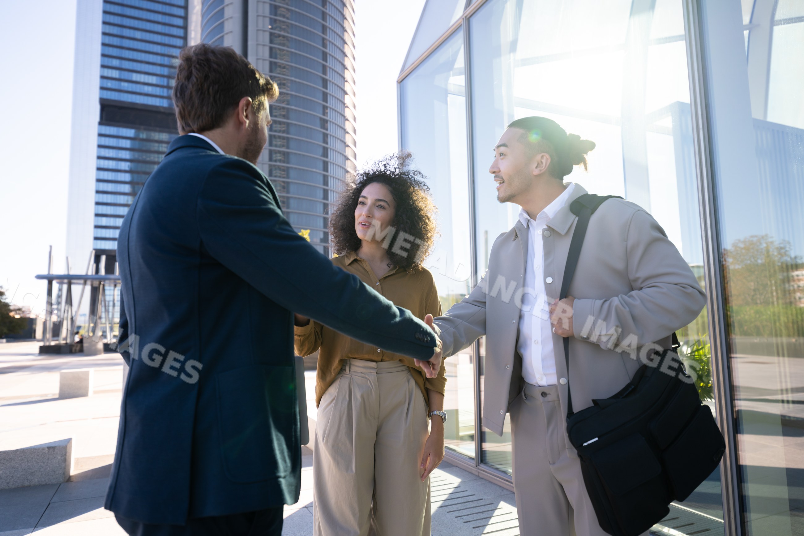 Business white professionals shaking hands outside modern building