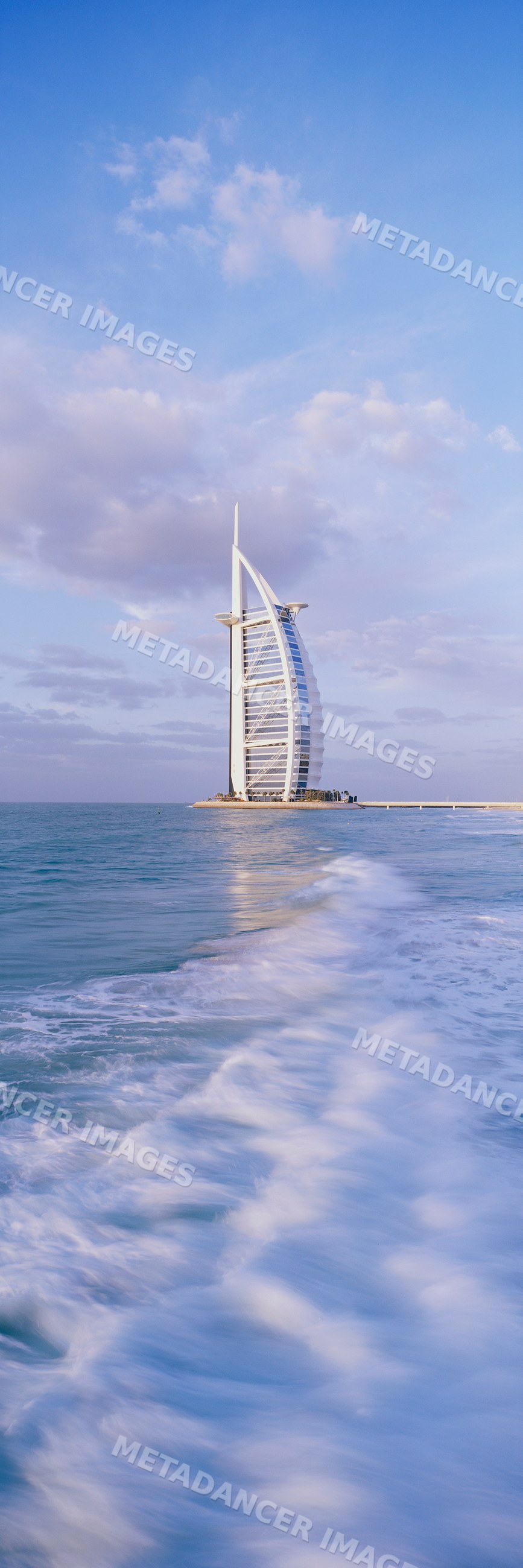 The burj al arab hotel stands on an artificial island amid sea waves