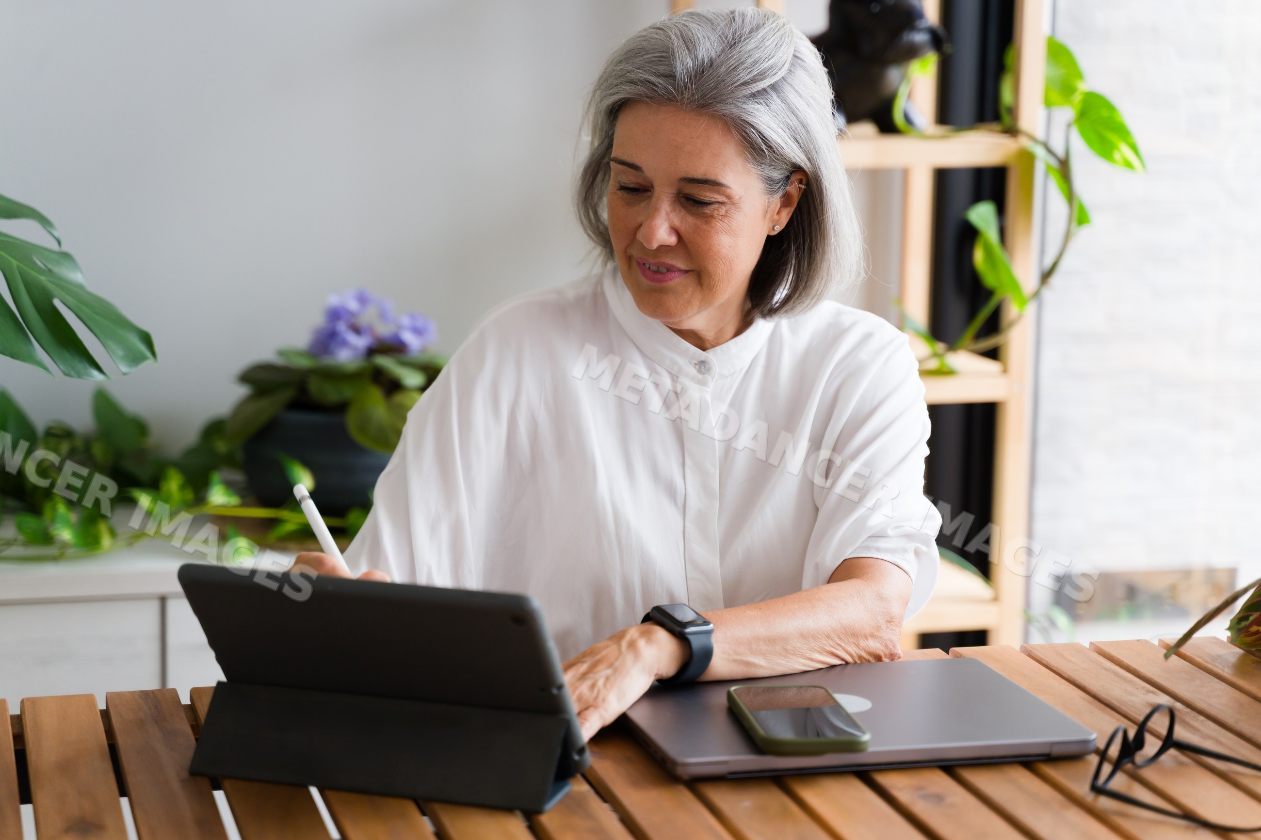 White Woman working on digital tablet with stylus pen at home office
