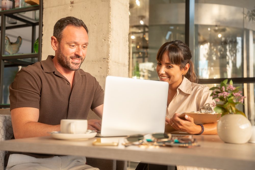 Coworkers using laptop in indoor cafe business meeting in Seville