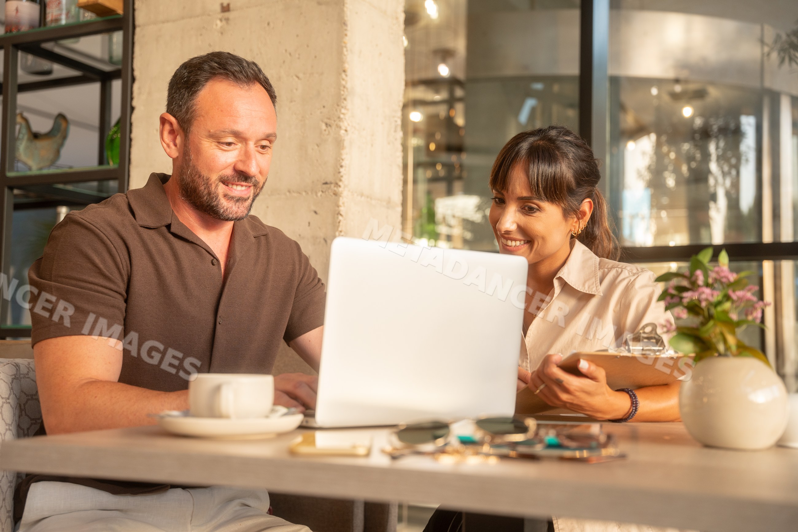 Coworkers using laptop in indoor cafe business meeting in Seville