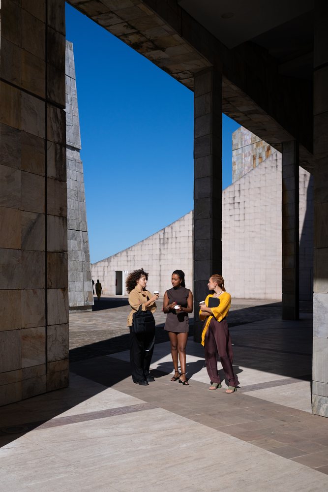 Three African American and white people conversing under modern plaza