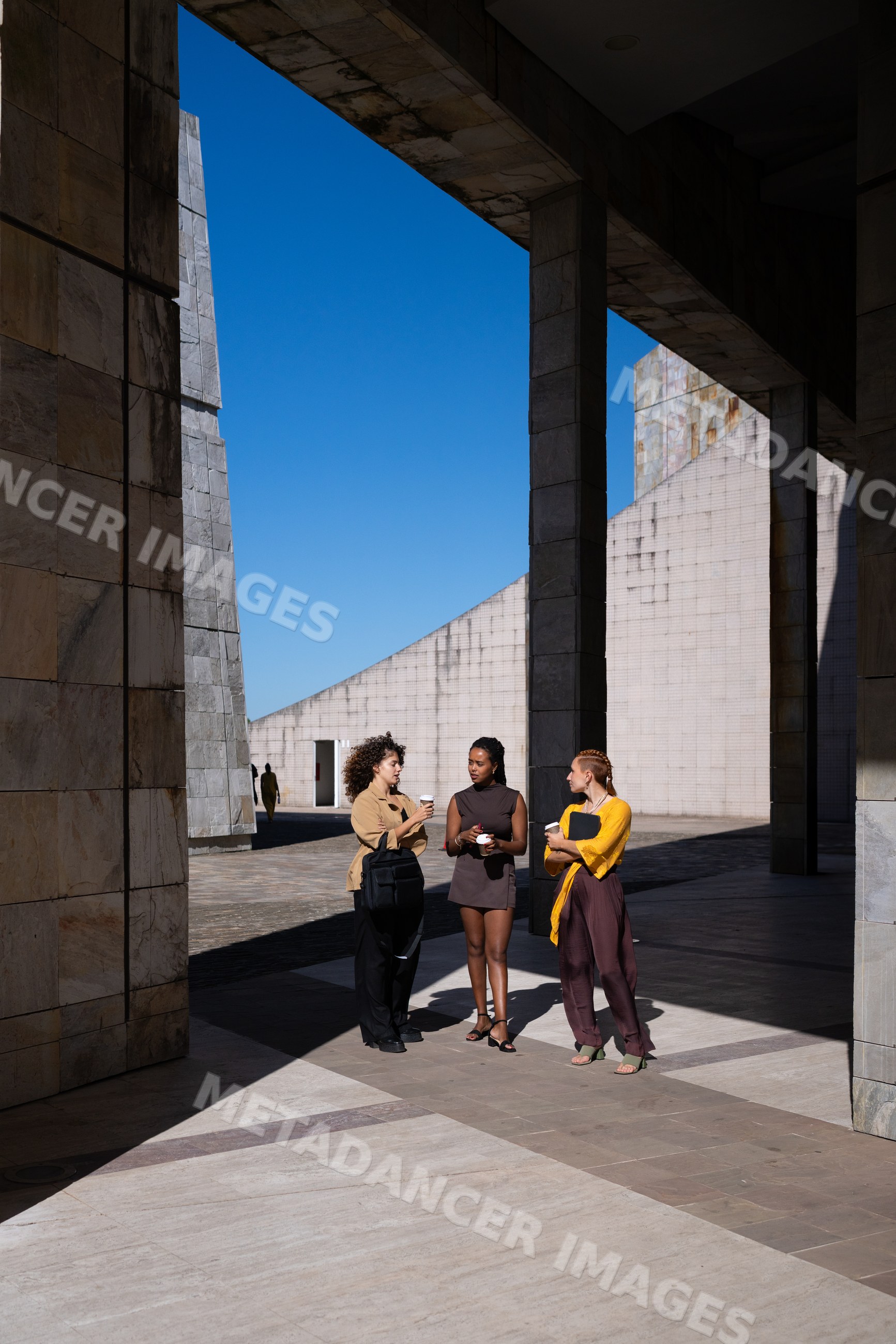Three African American and white people conversing under modern plaza
