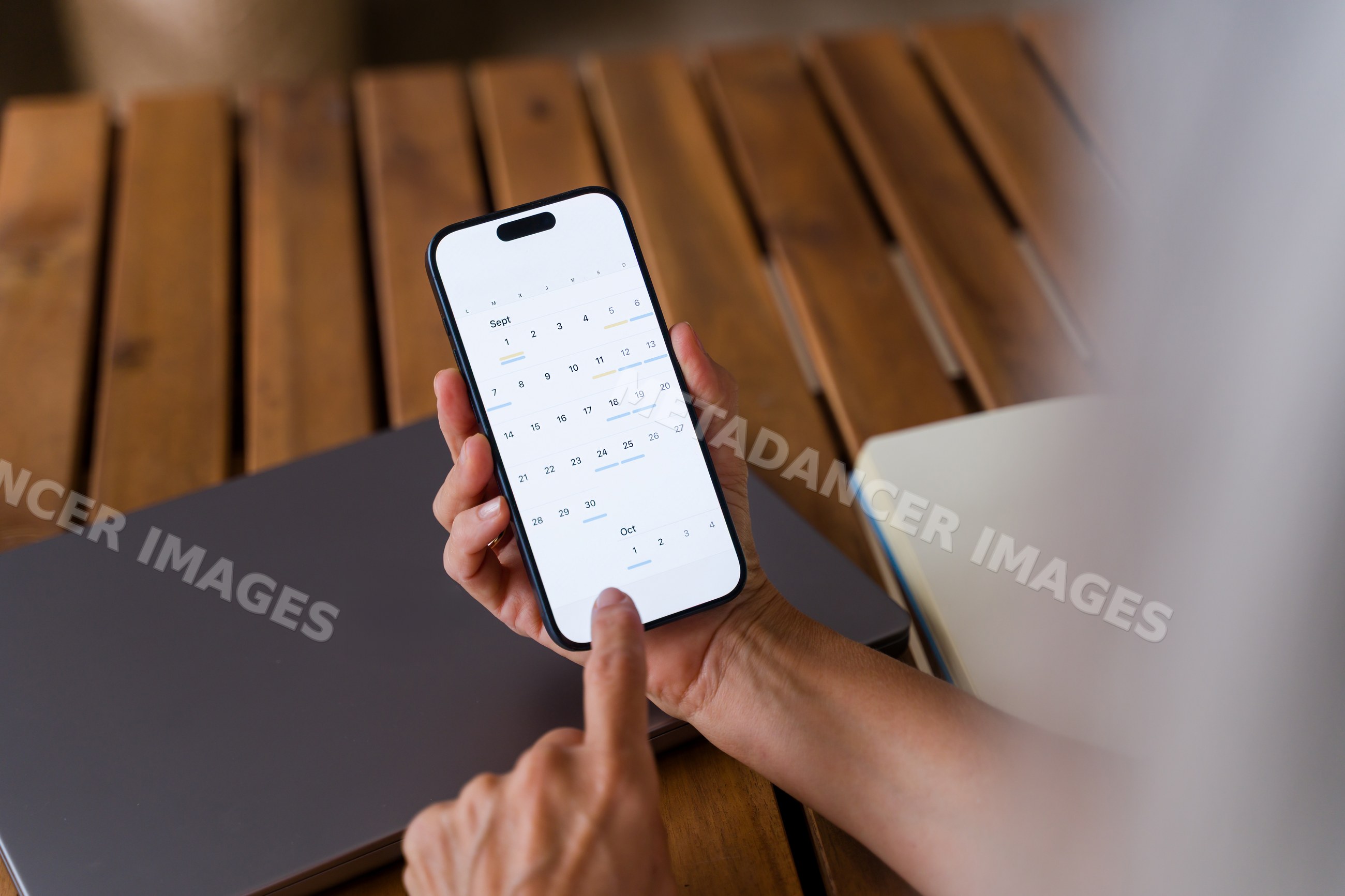 Digital calendar app displayed on smartphone held above wooden table