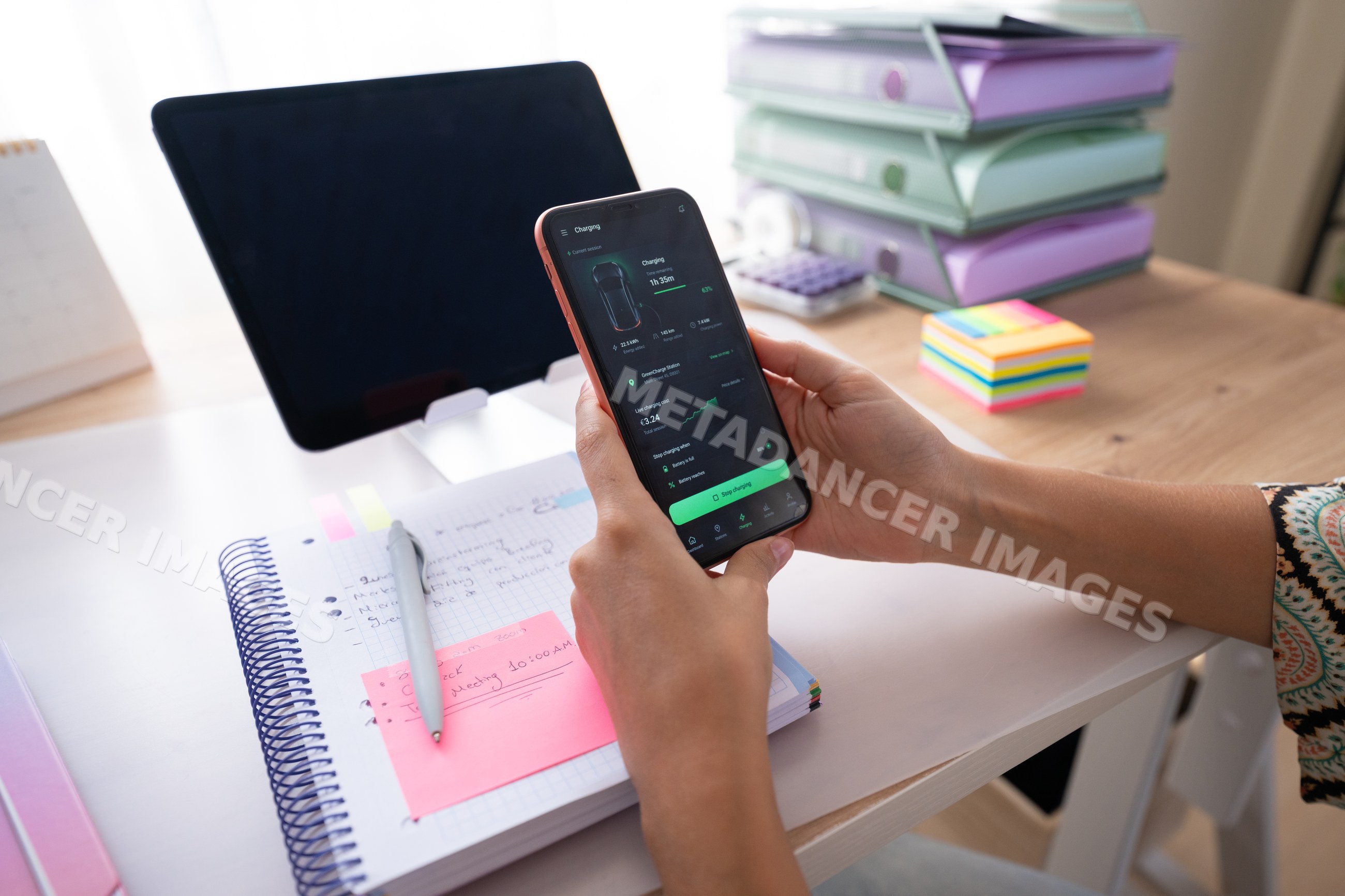 Hand holding smartphone displaying charging status by notebook