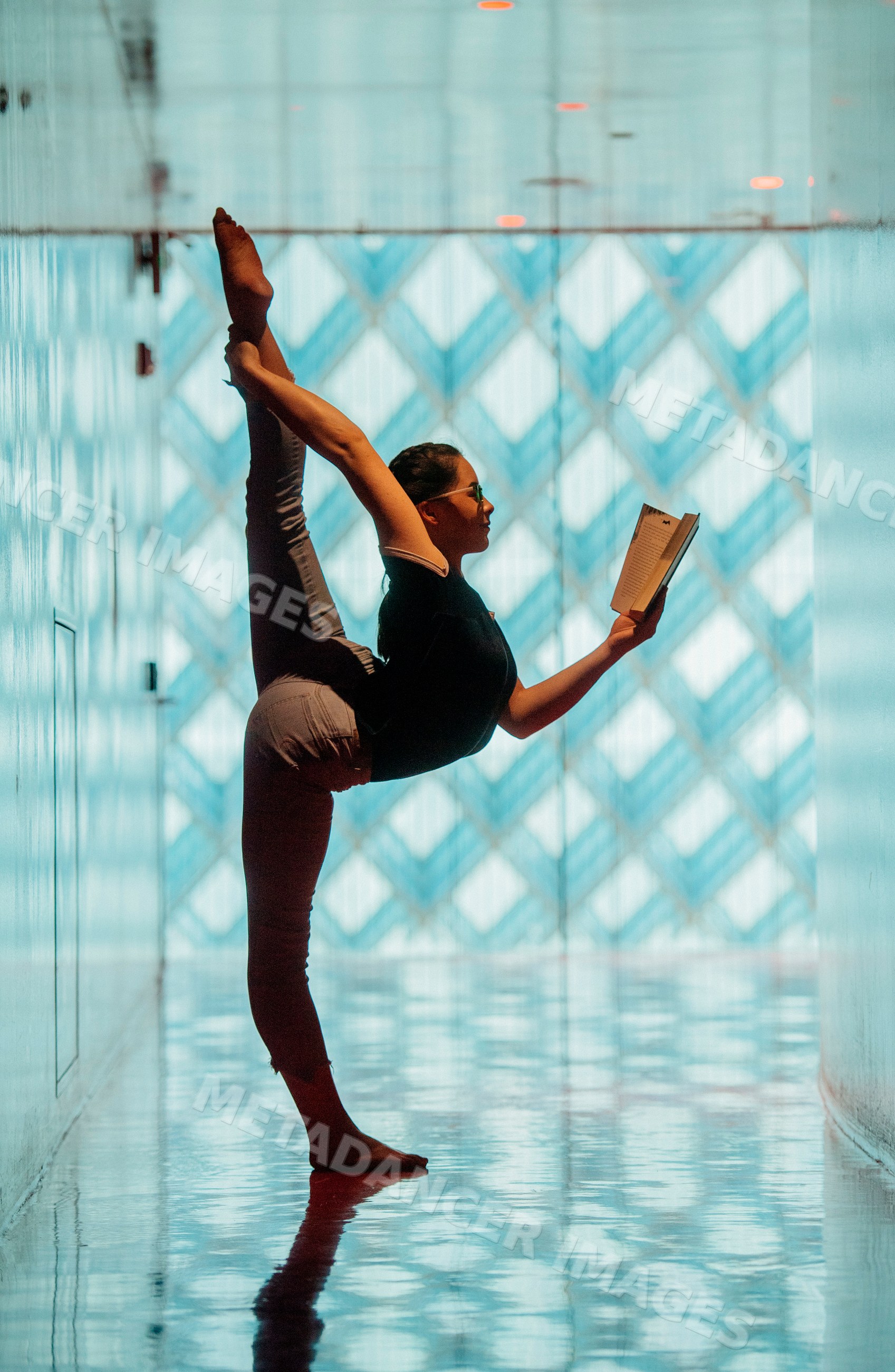 A woman reads a book while performing a high leg stretch