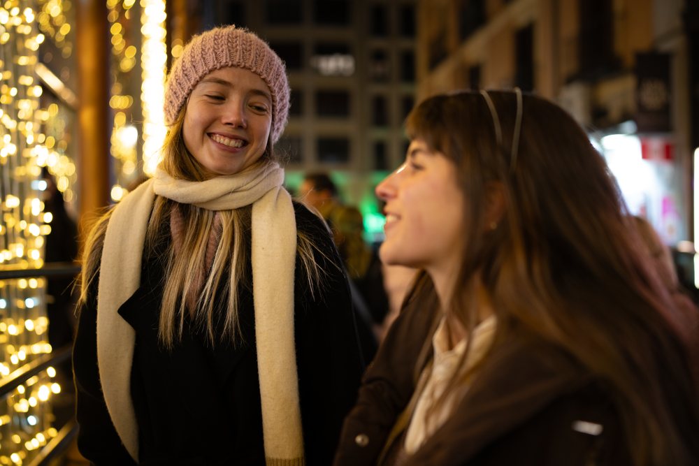 Two white women smiling and talking at a christmas market