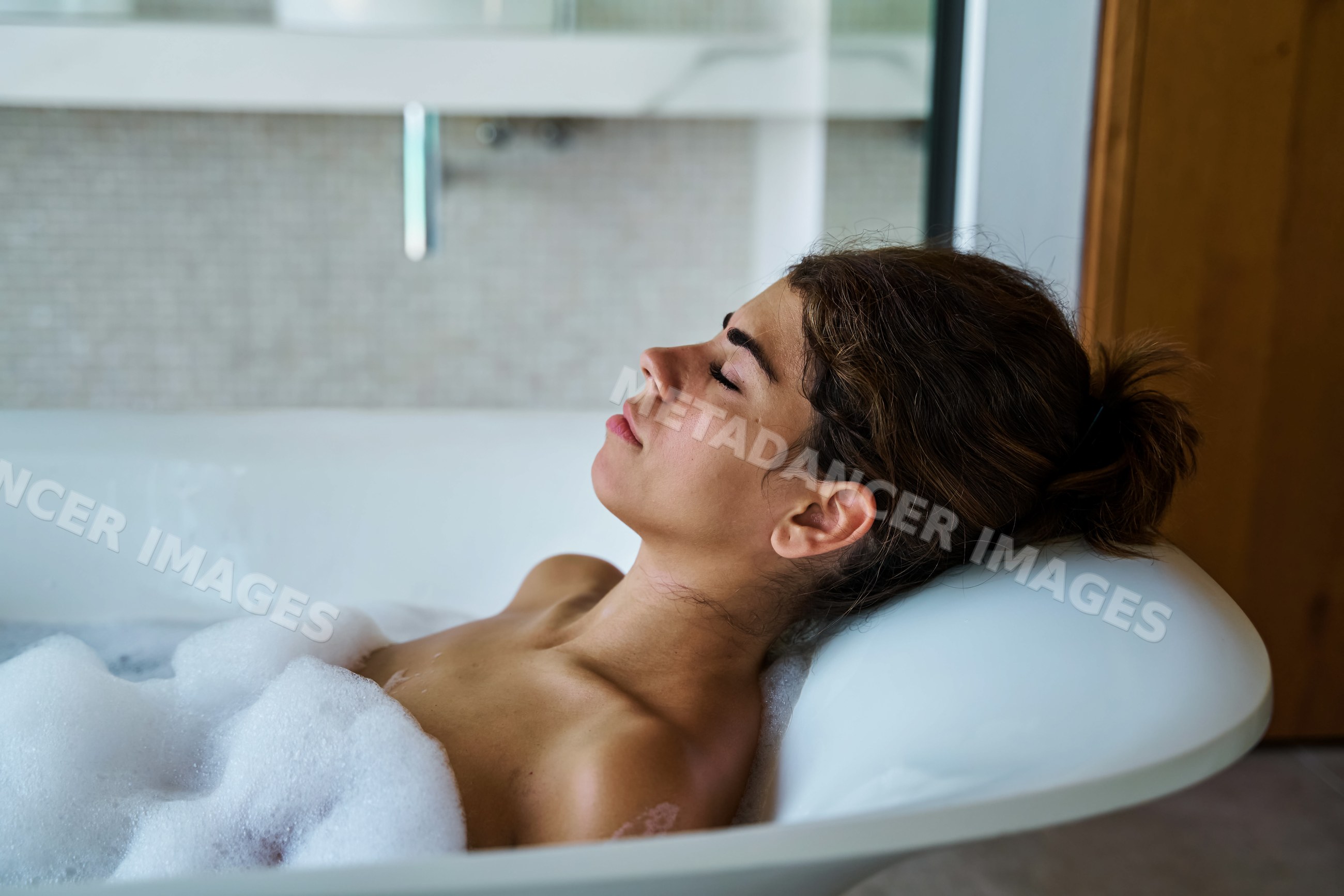 A white woman relaxes peacefully in a bubbly bath