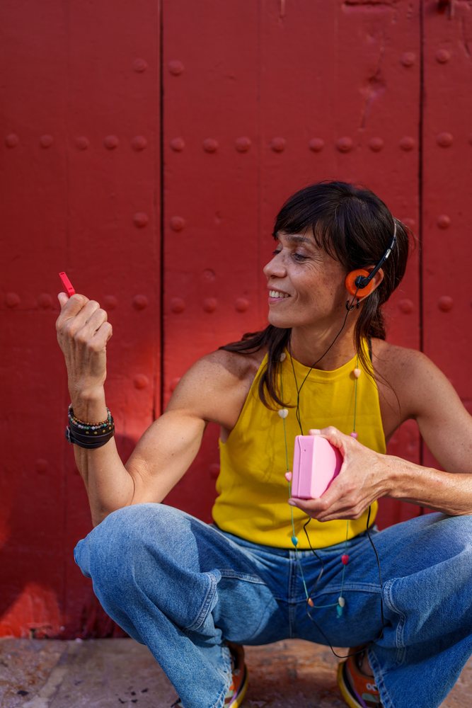 Hispanic woman listening to music with orange headphones outdoors