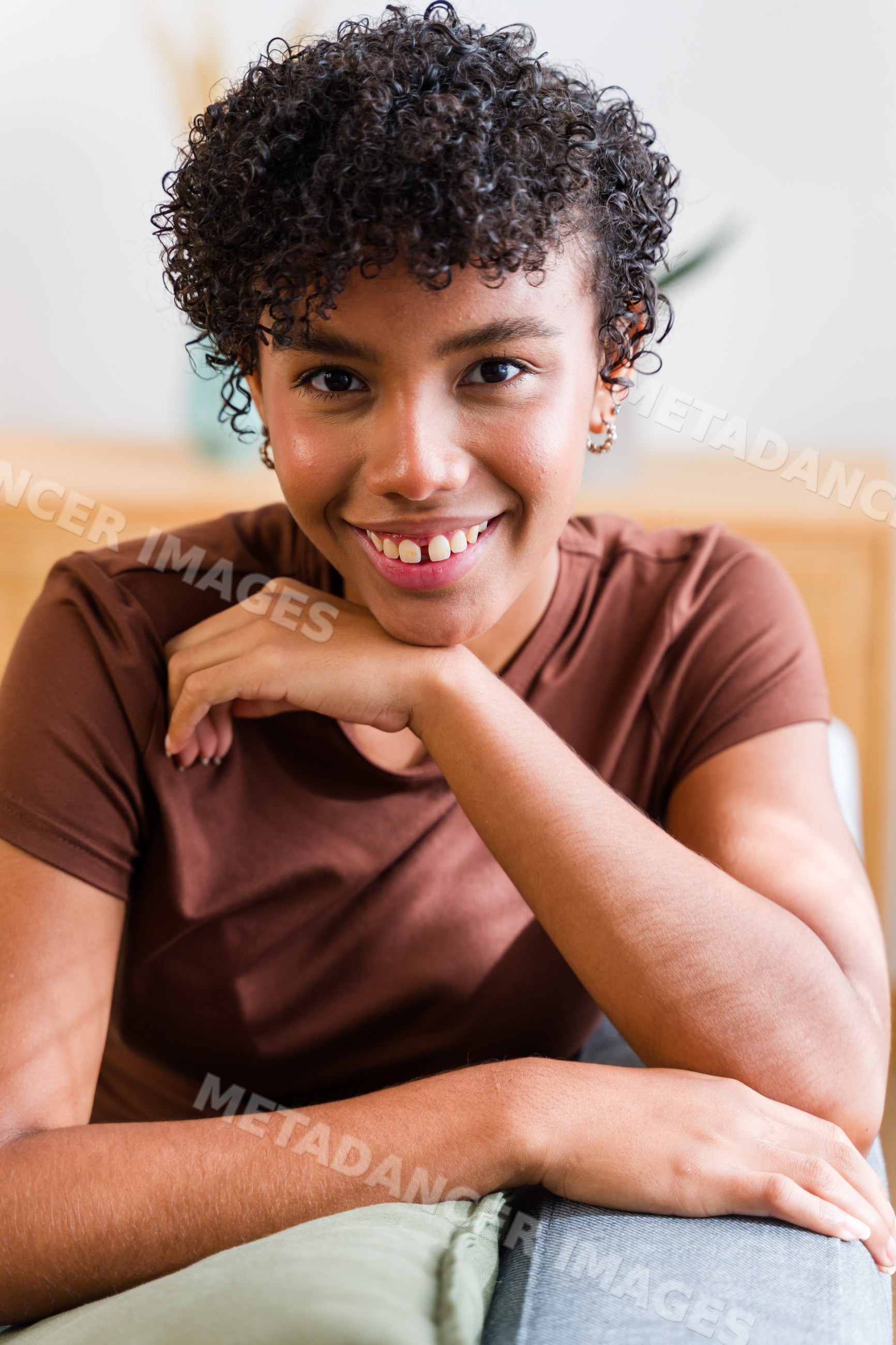 African American woman smiling and leaning on sofa indoors