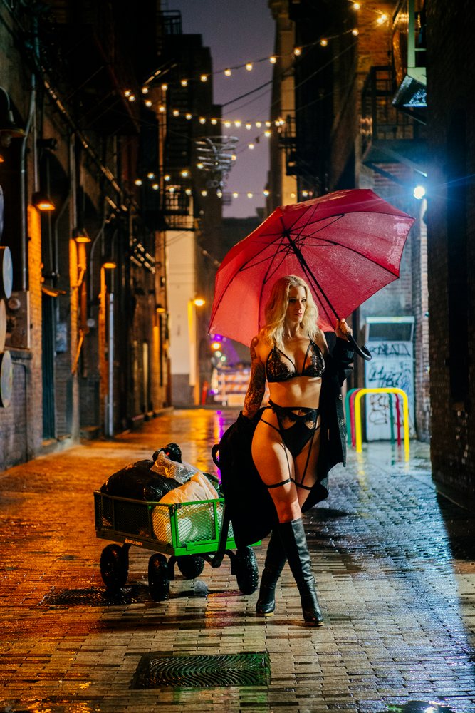 White woman walking in black lingerie with red umbrella in rainy