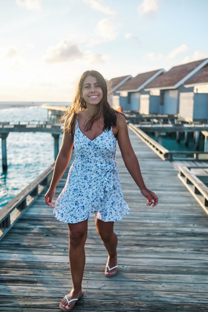 A white woman walks along a wooden boardwalk at a Maldives resort