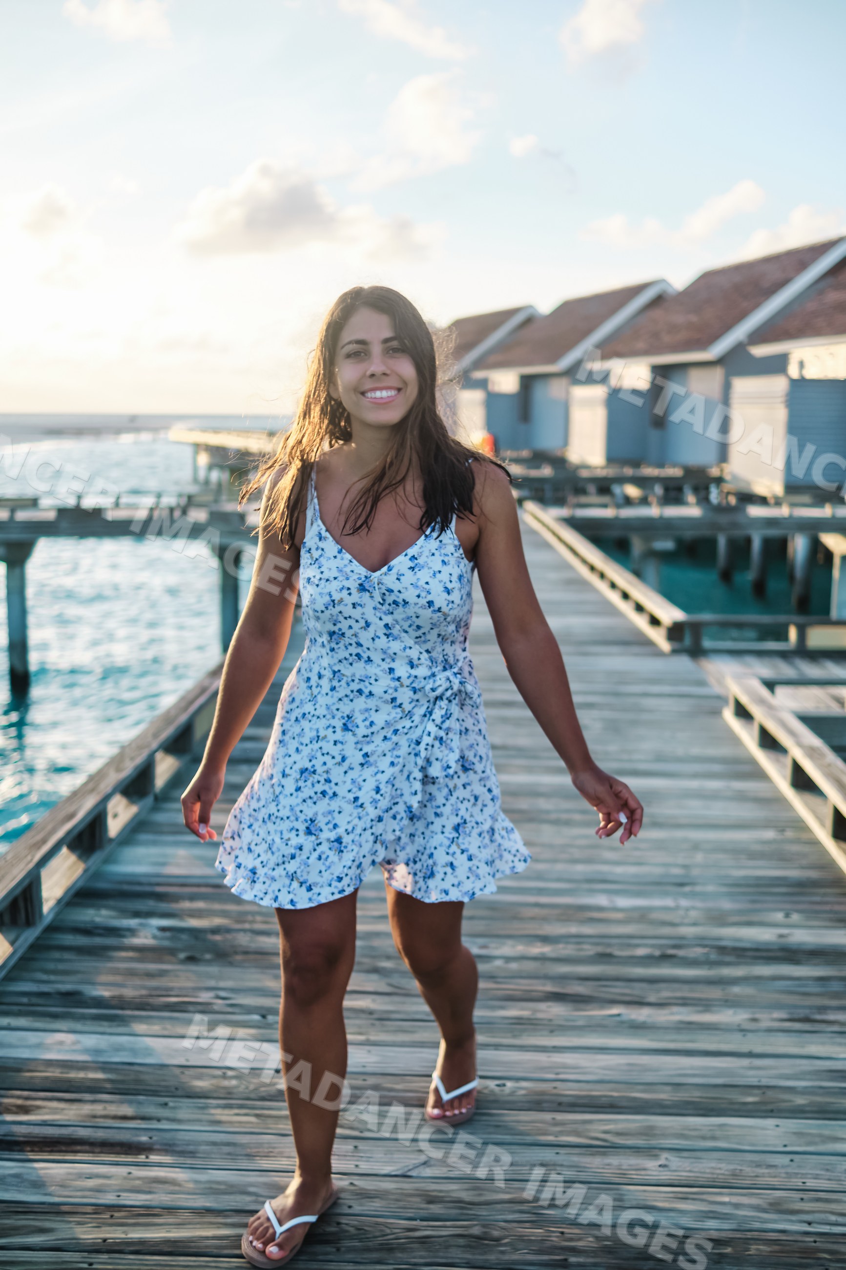 A white woman walks along a wooden boardwalk at a Maldives resort