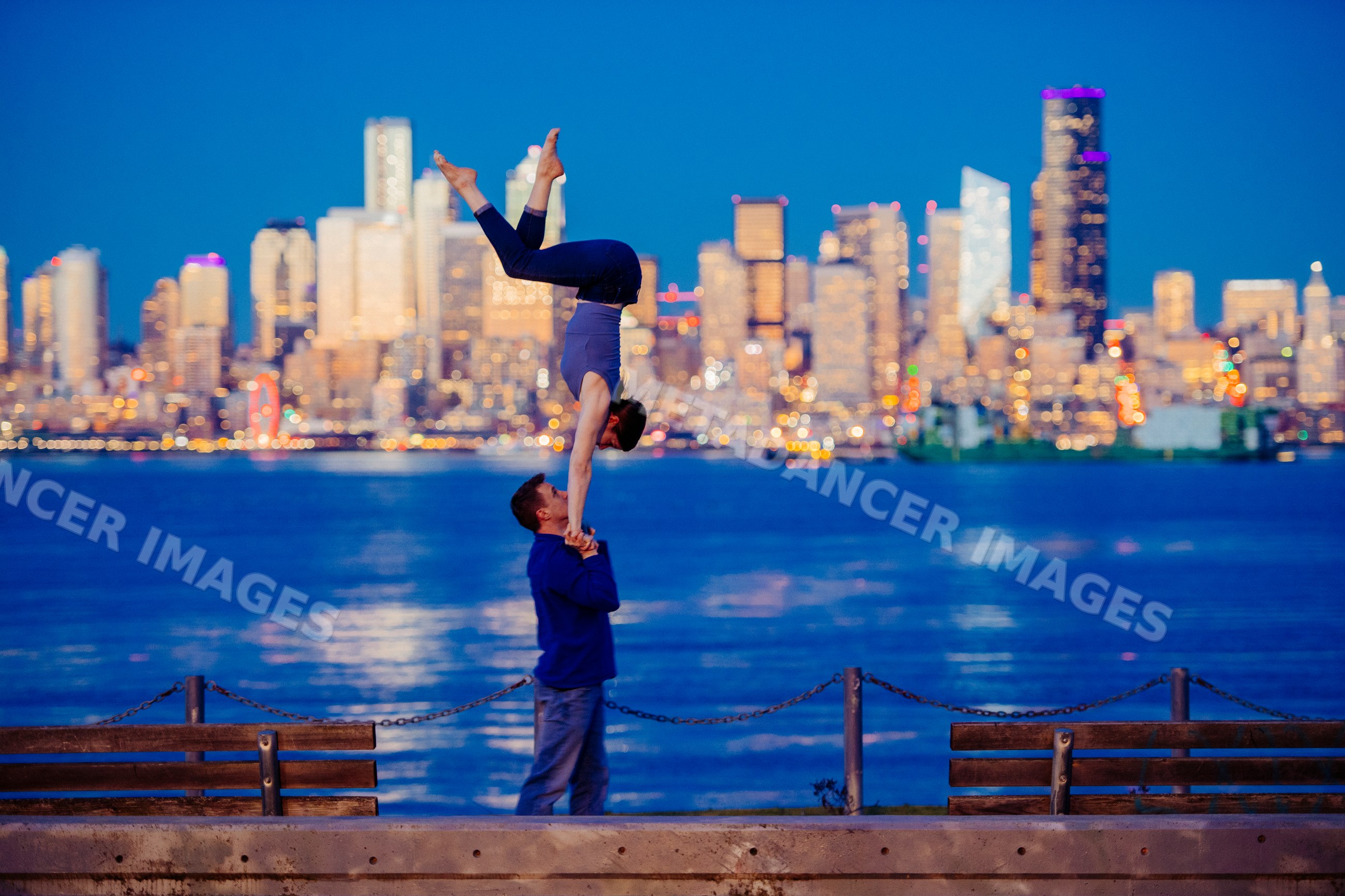 Partner acrobatics yoga handstand by Seattle waterfront at dusk