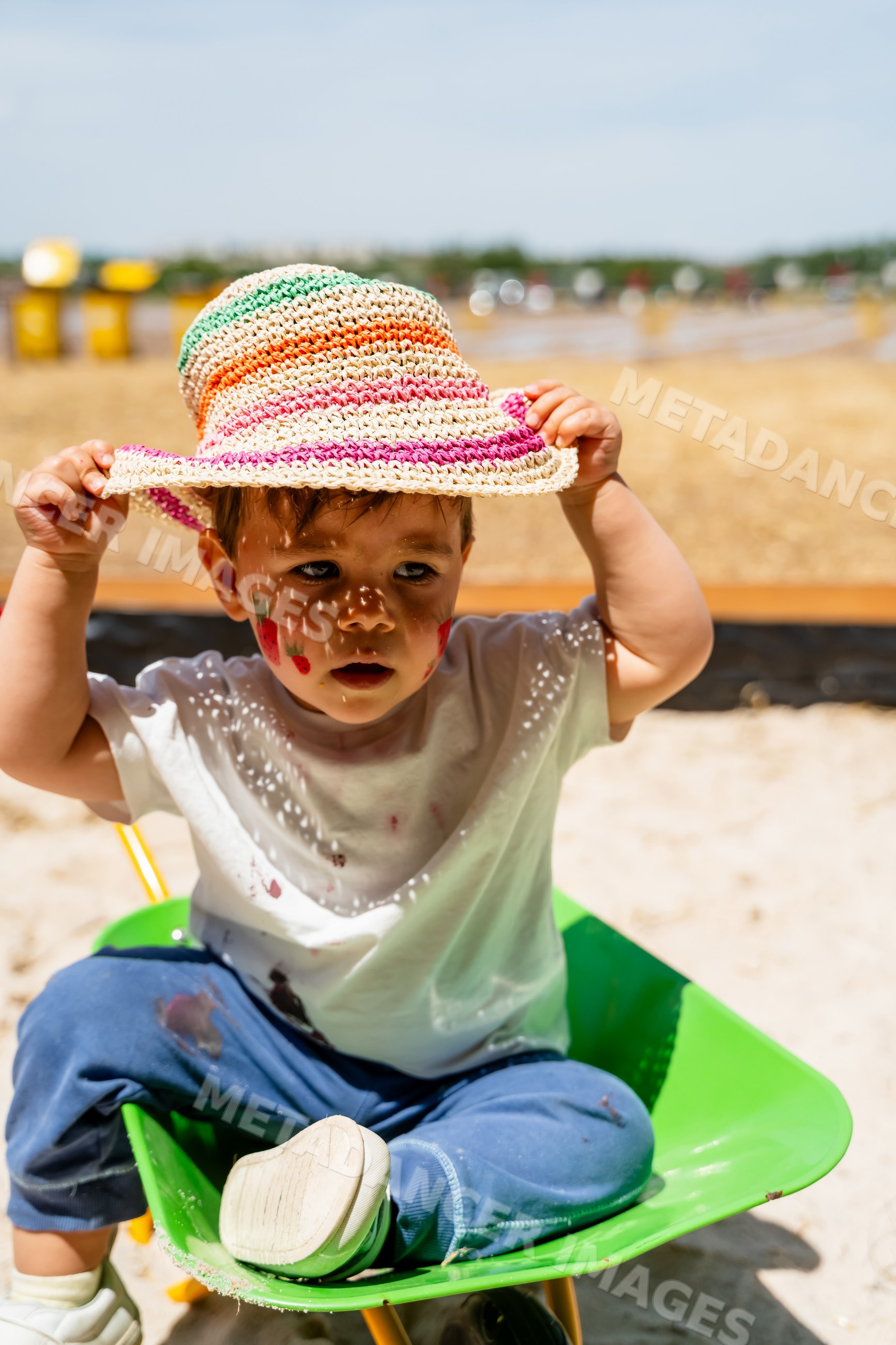Toddler sitting with face paint in a wheelbarrow outdoors