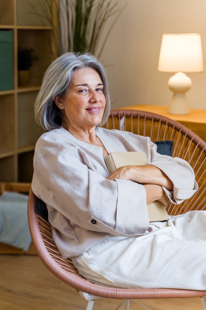 Smiling middle-aged white woman holding a book seated indoors