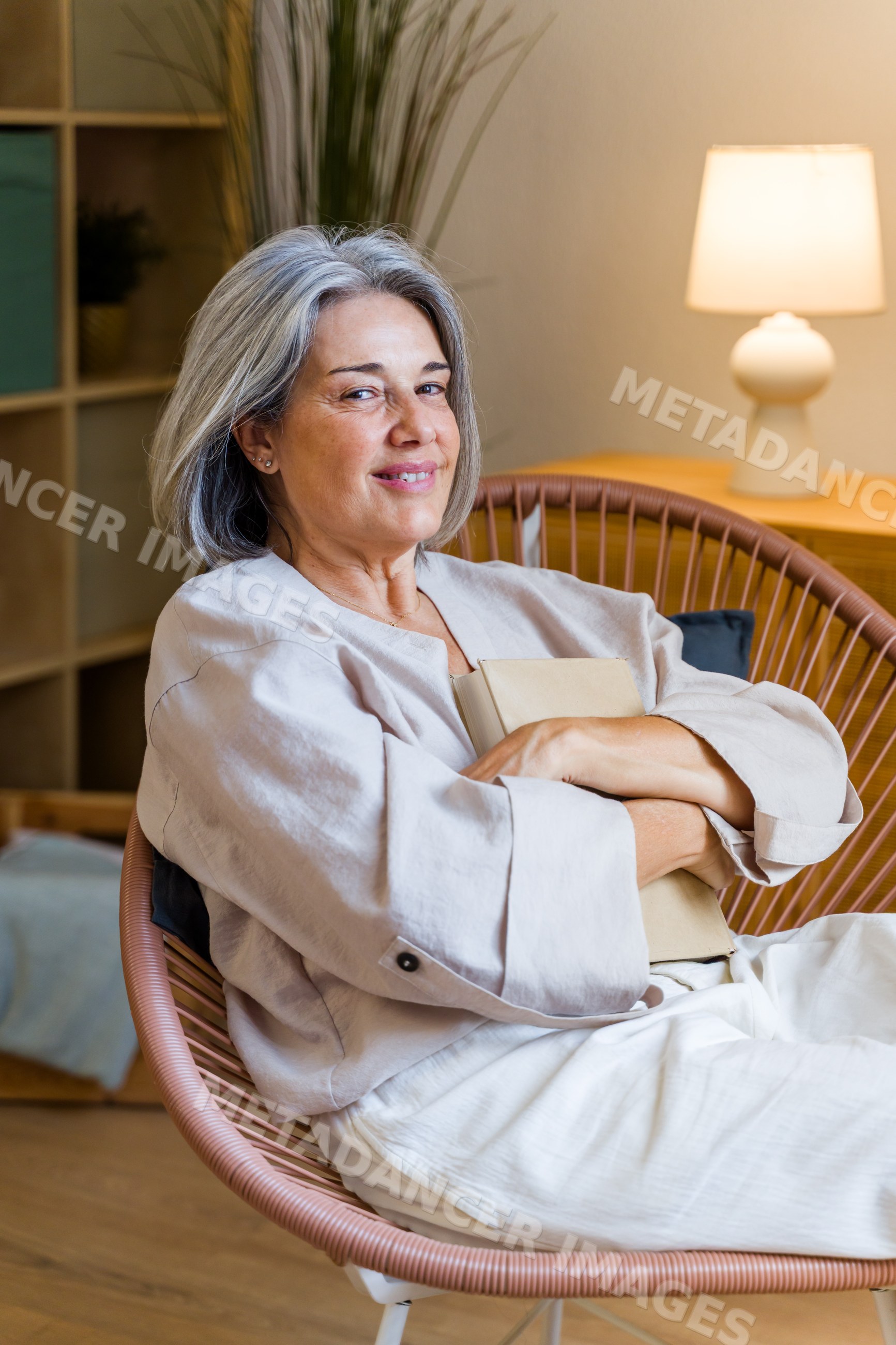Smiling middle-aged white woman holding a book seated indoors