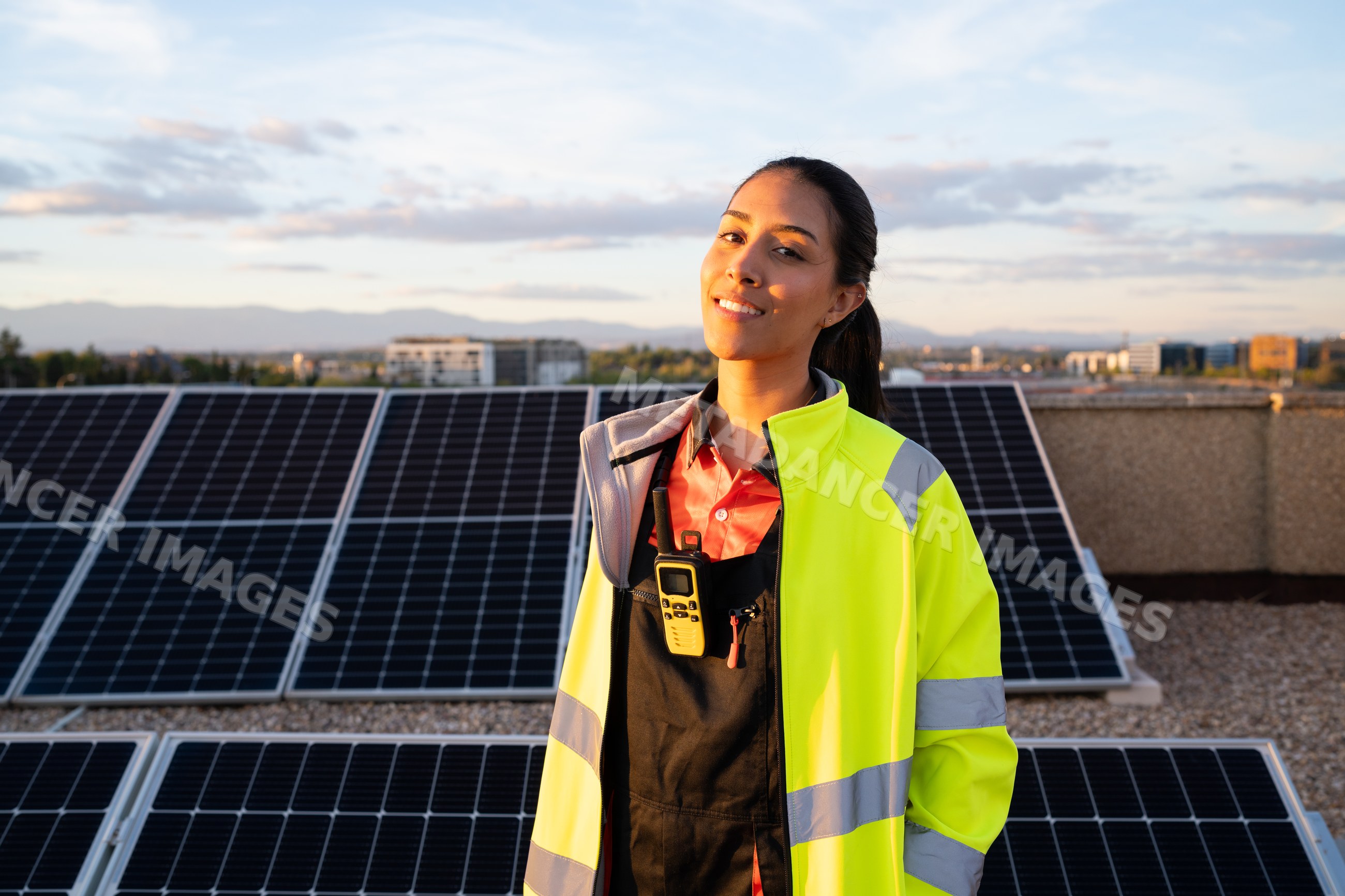 Hispanic woman engineer inspecting solar panels on rooftop at sunset