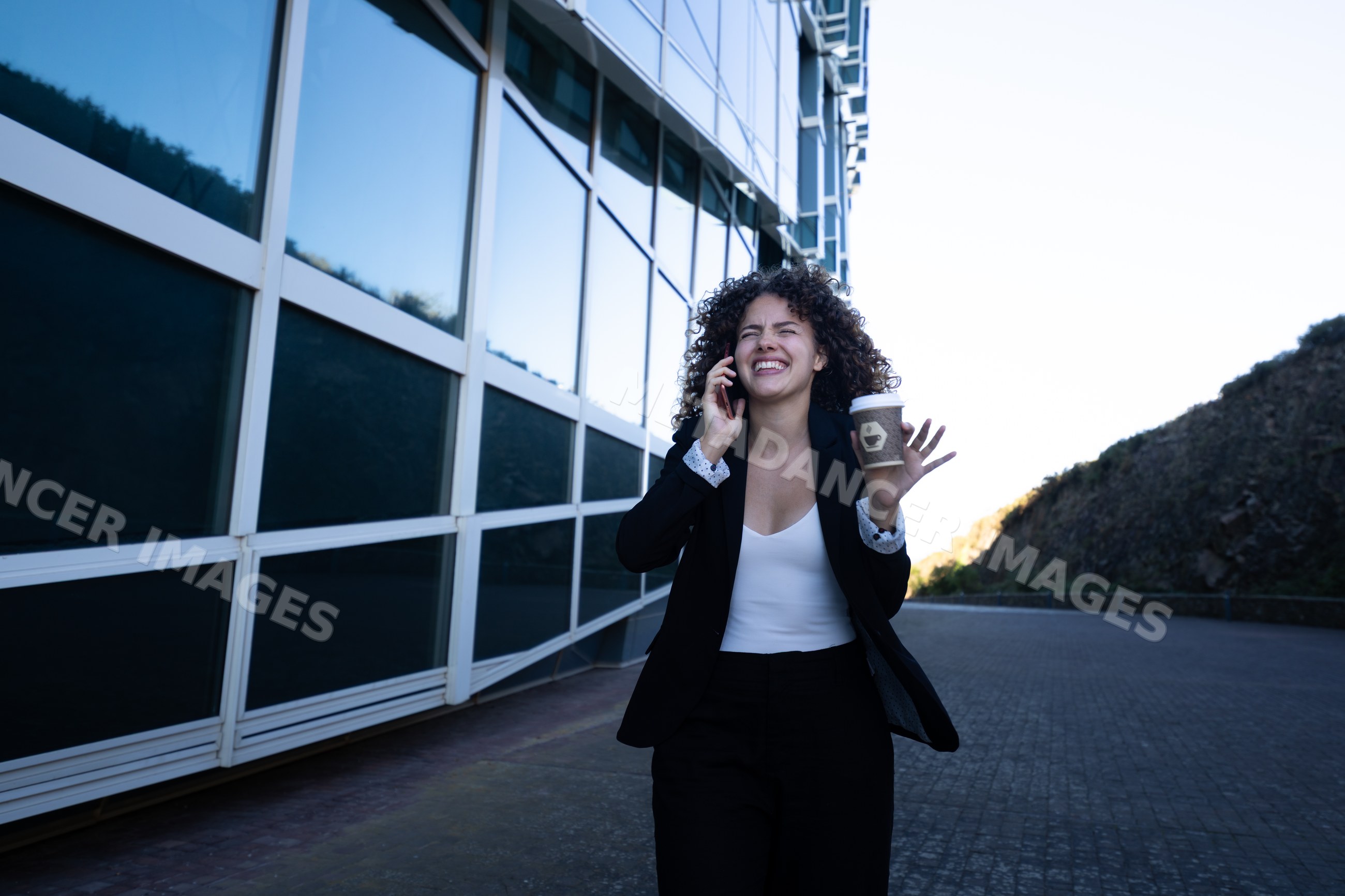 White professional woman smiling on phone with coffee outside modern