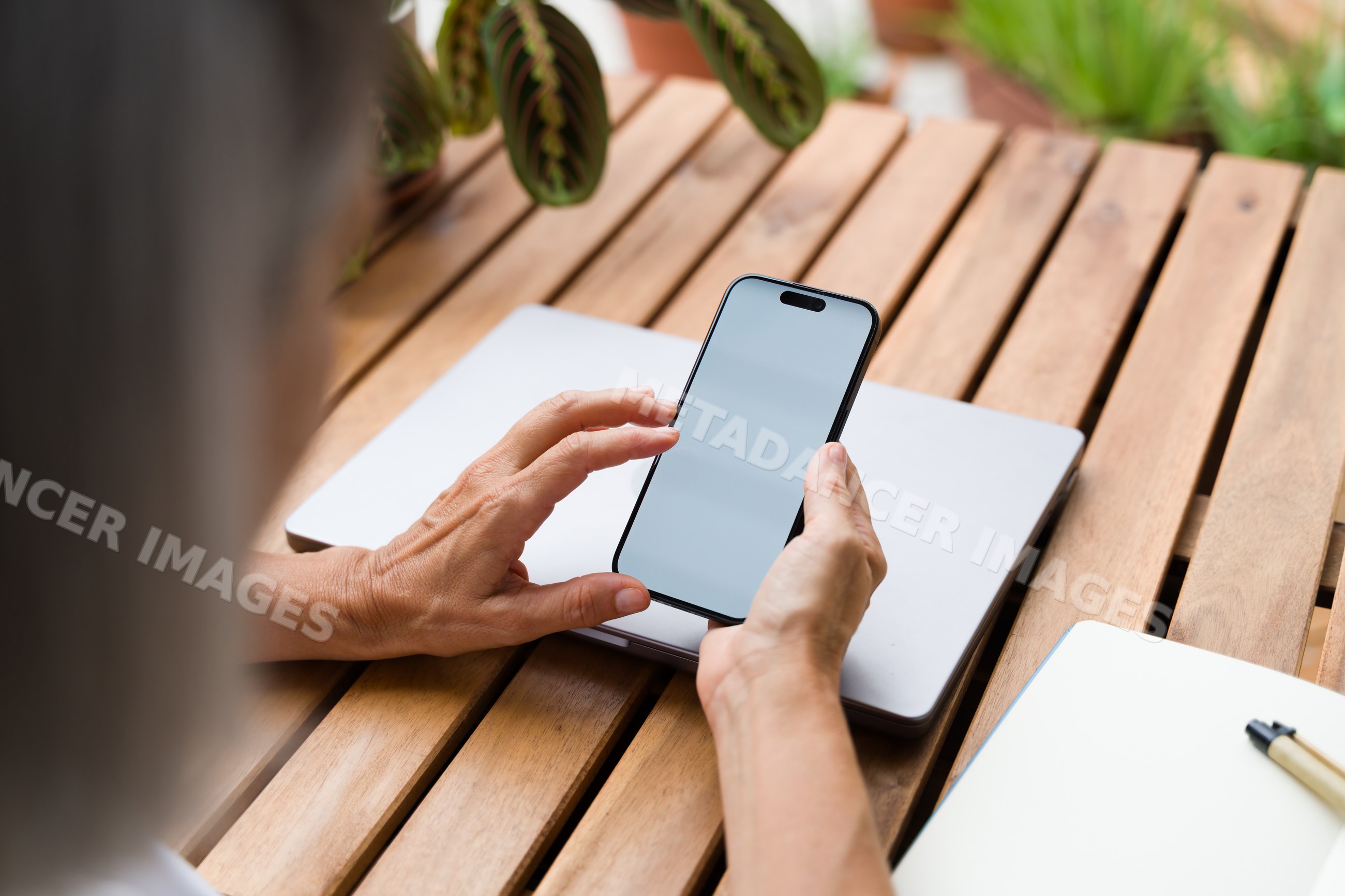 Smartphone held over closed laptop on wooden table