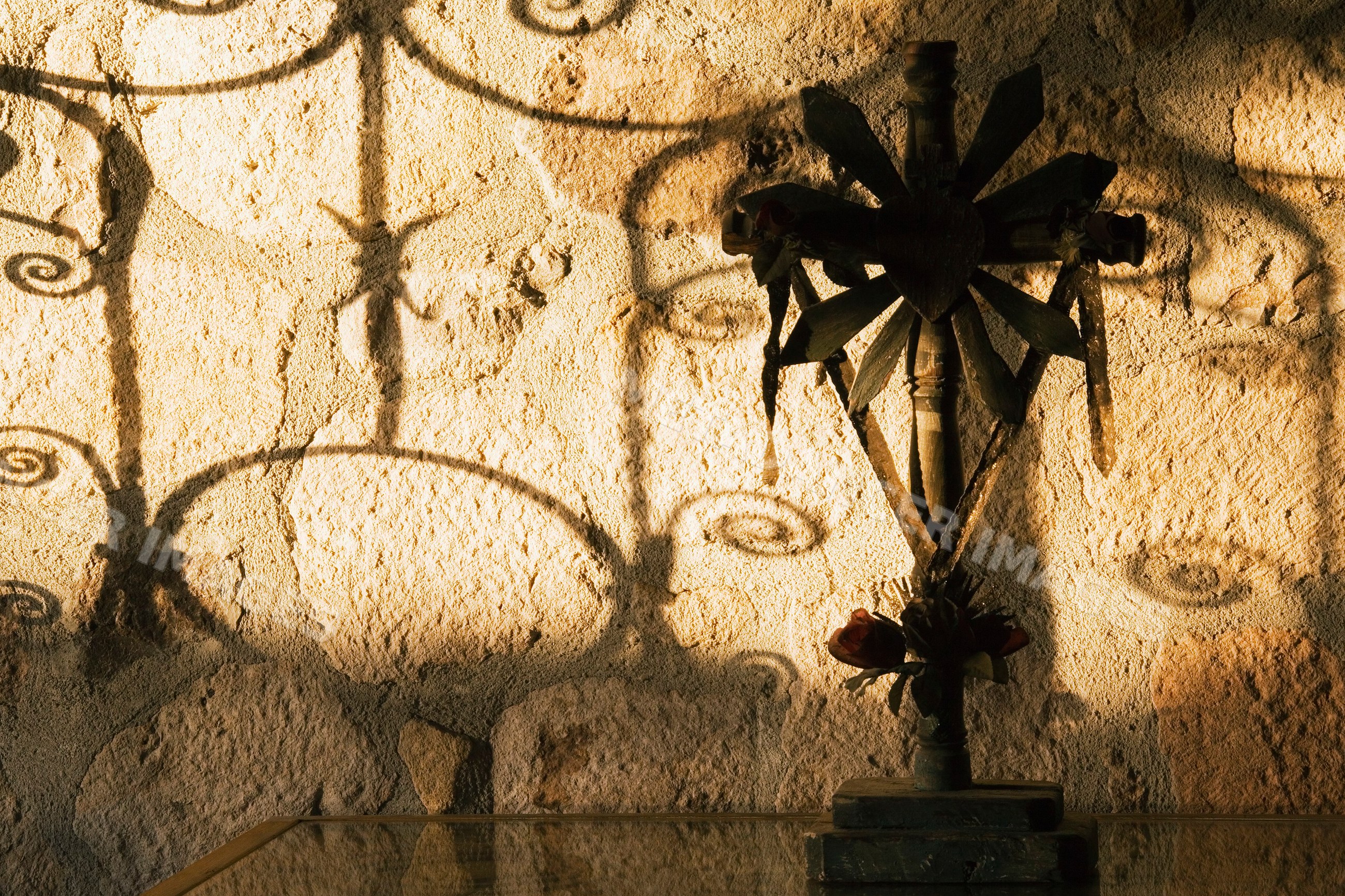 Cross casting shadows on textured wall