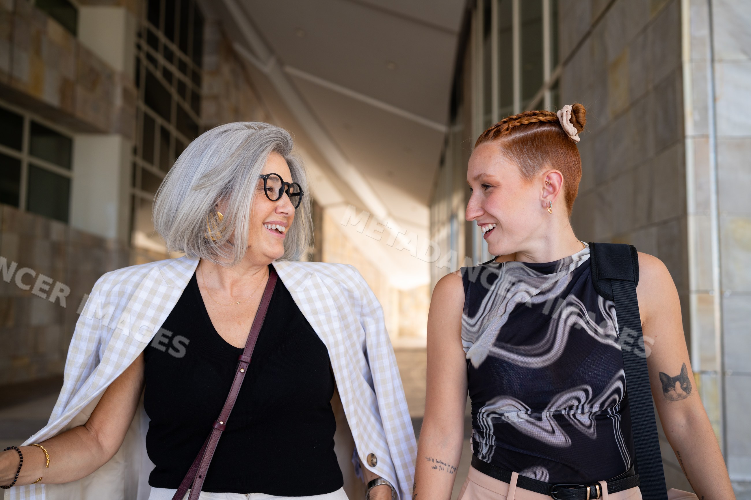 Businesswomen walking and smiling outside modern urban building