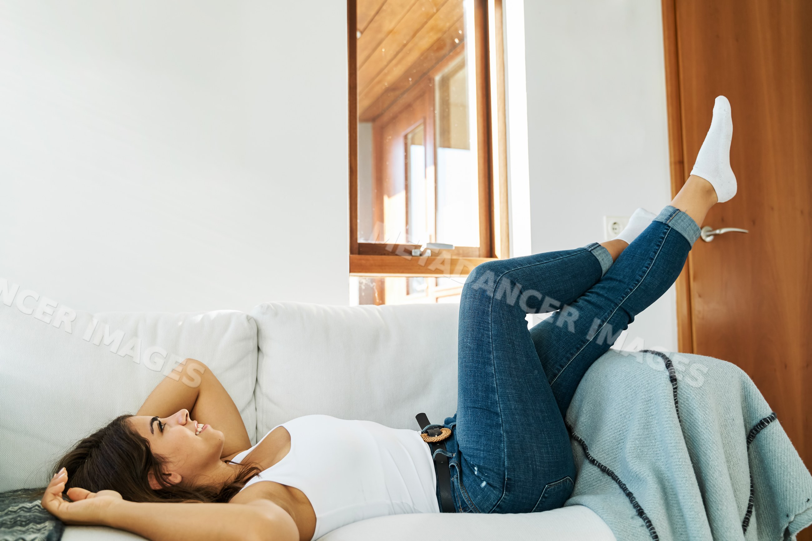 A young white woman relaxing on a couch in a cozy living room