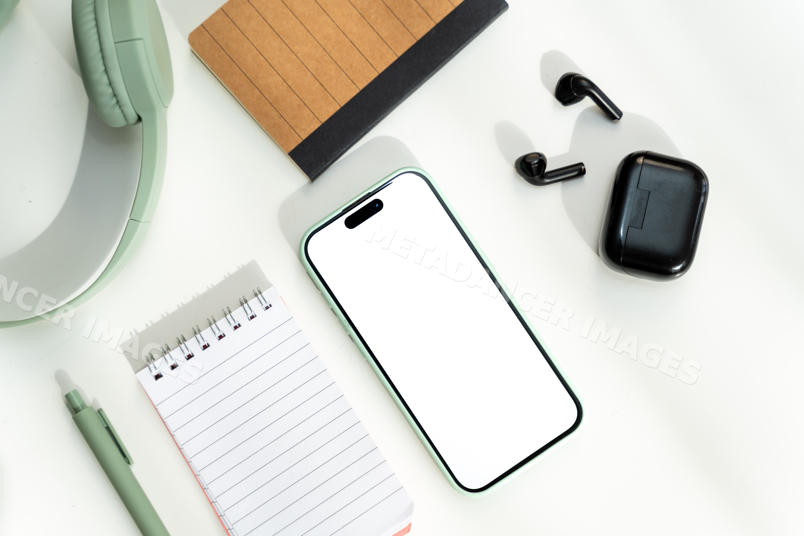 Smartphone with wireless earbuds and office supplies on white desk