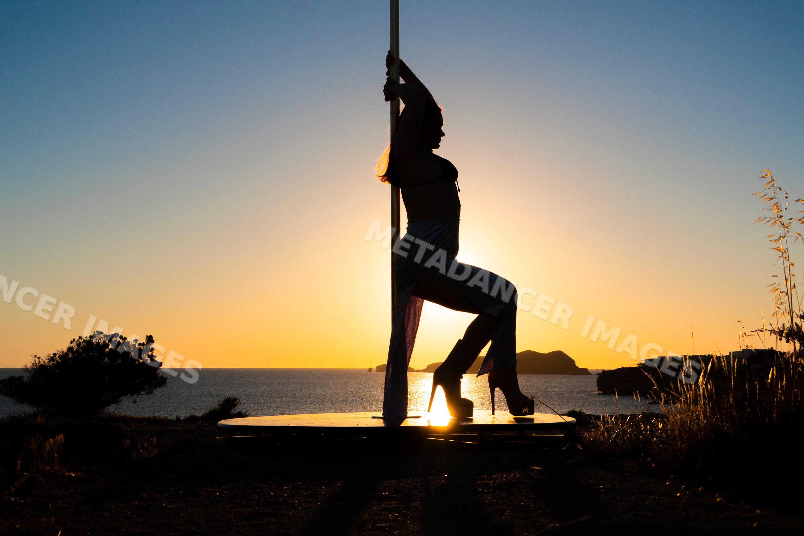 White woman performing pole dance silhouette at sunset in Ibiza, Spain