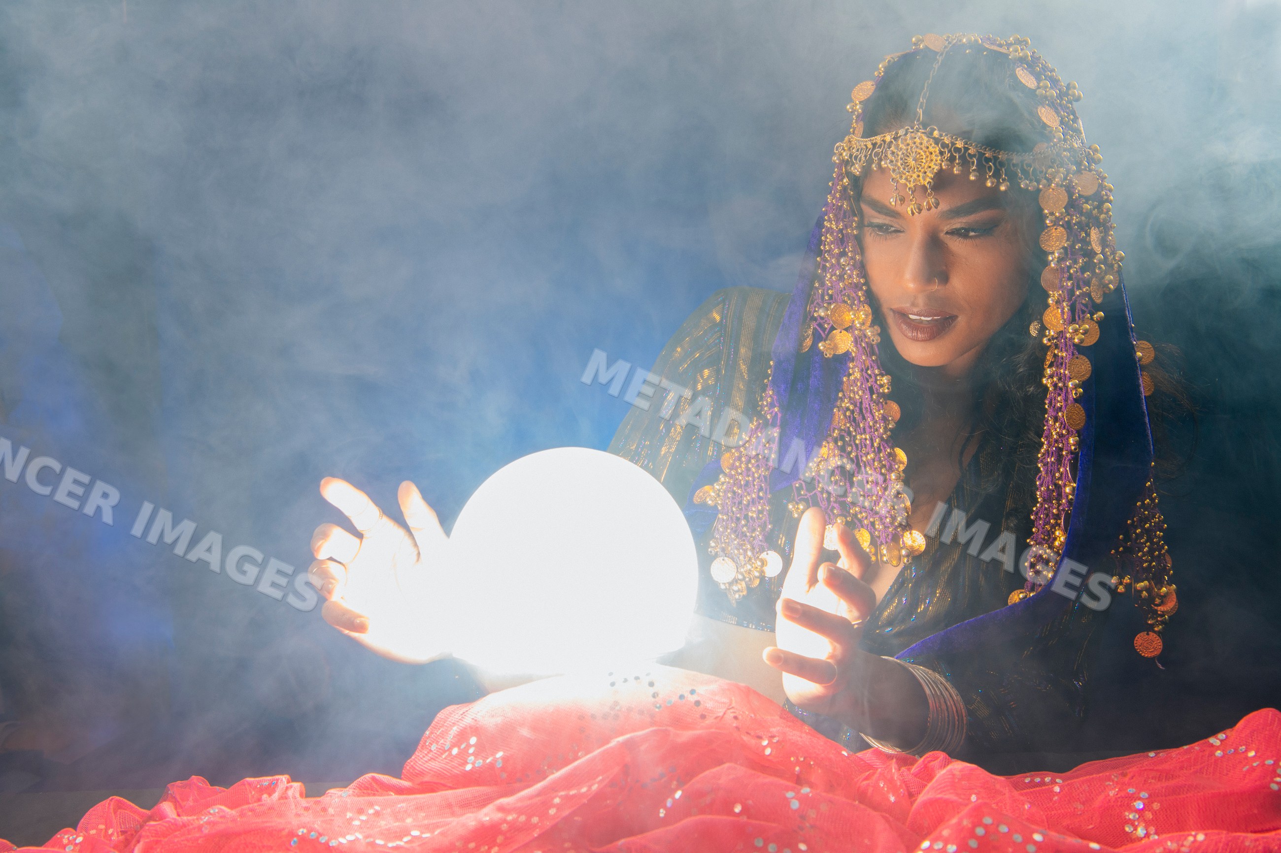 A fortune teller studies a glowing crystal ball