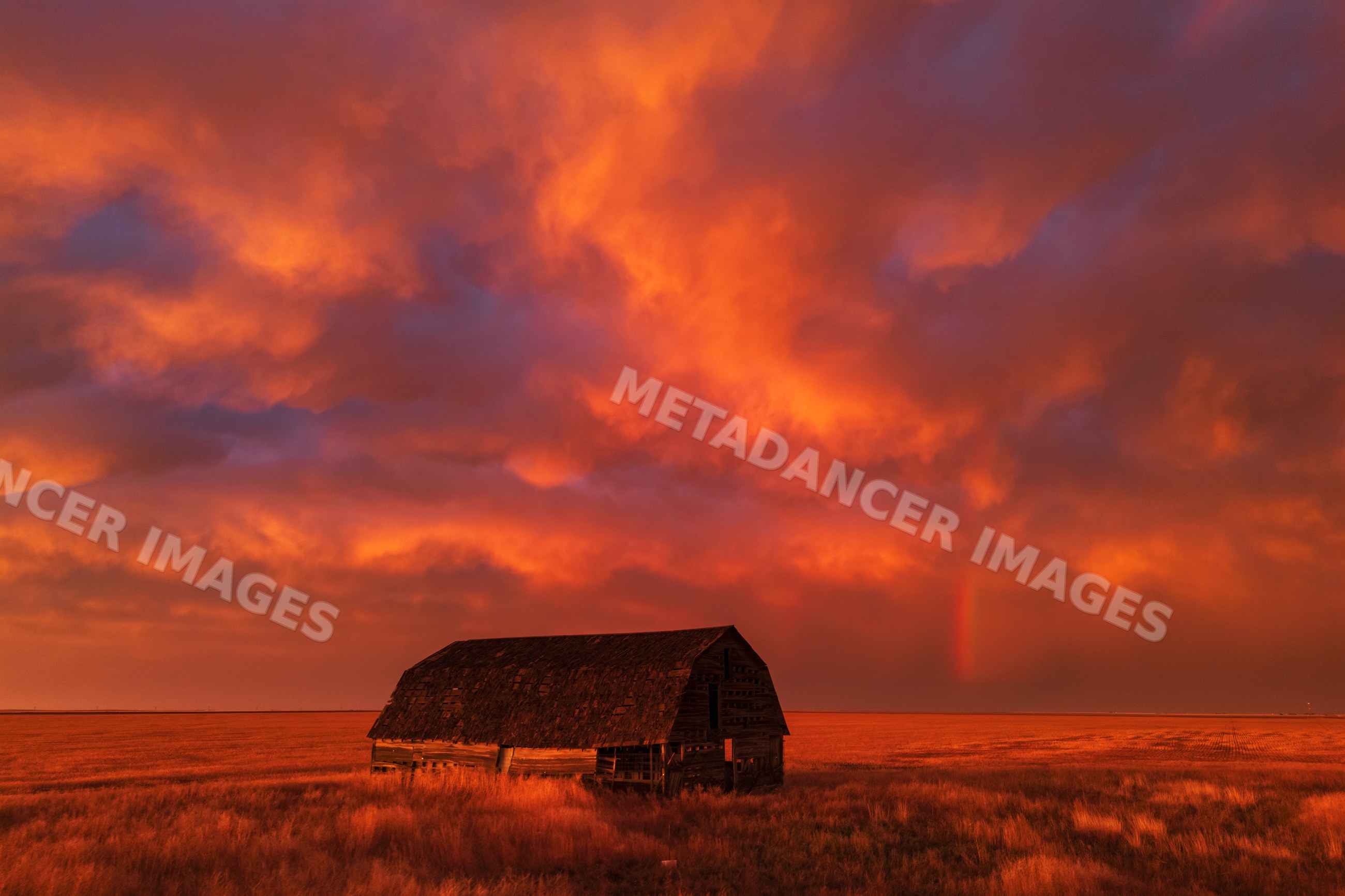 Old barn at Sunset with Rainbow and storm clouds in eva oklahoma