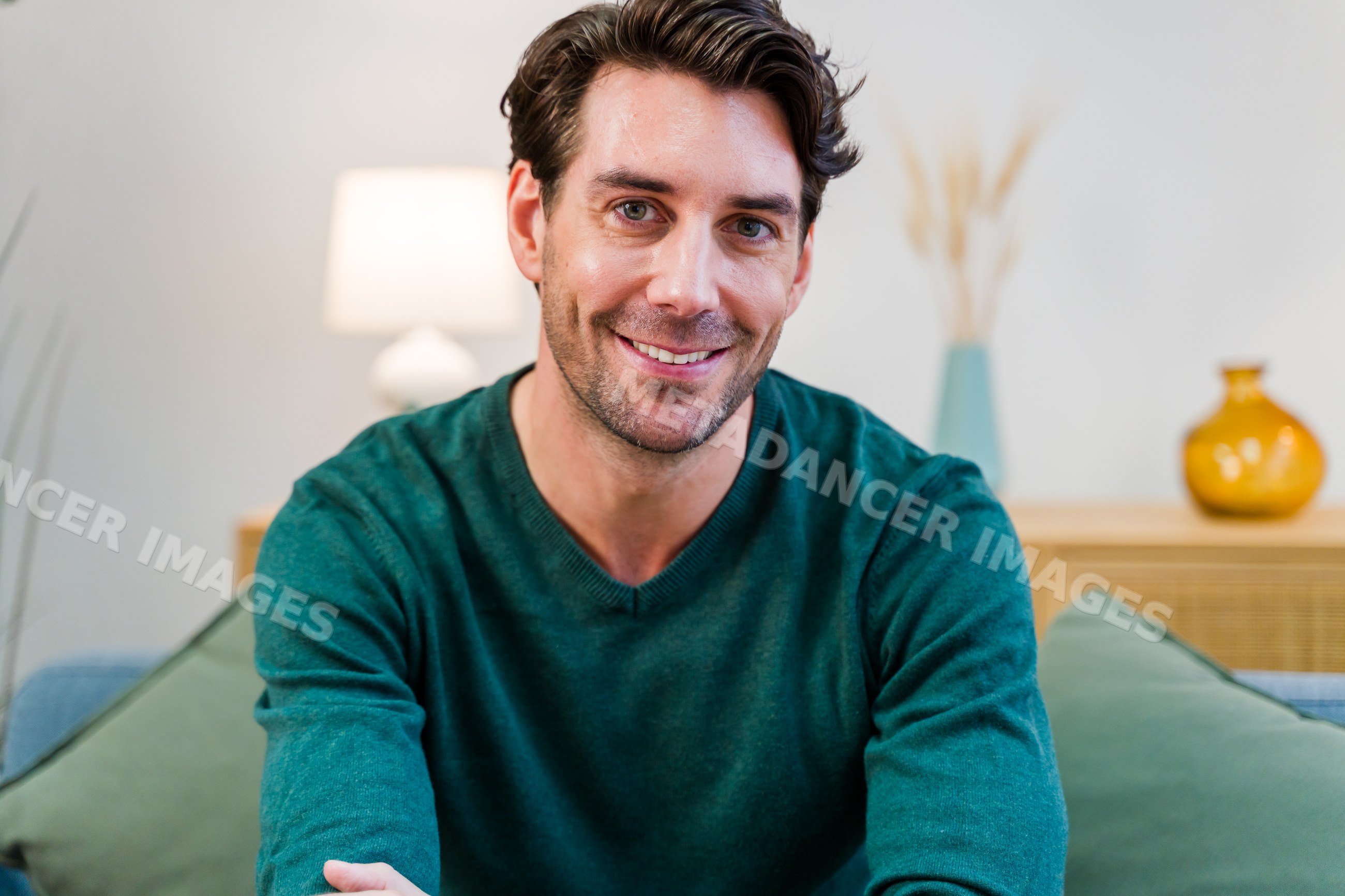 White man smiling seated on couch in casual living room interior